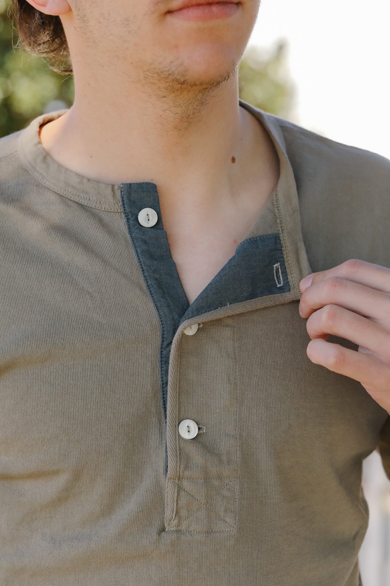 Close-up of a person wearing a green shirt with a collar and buttons.