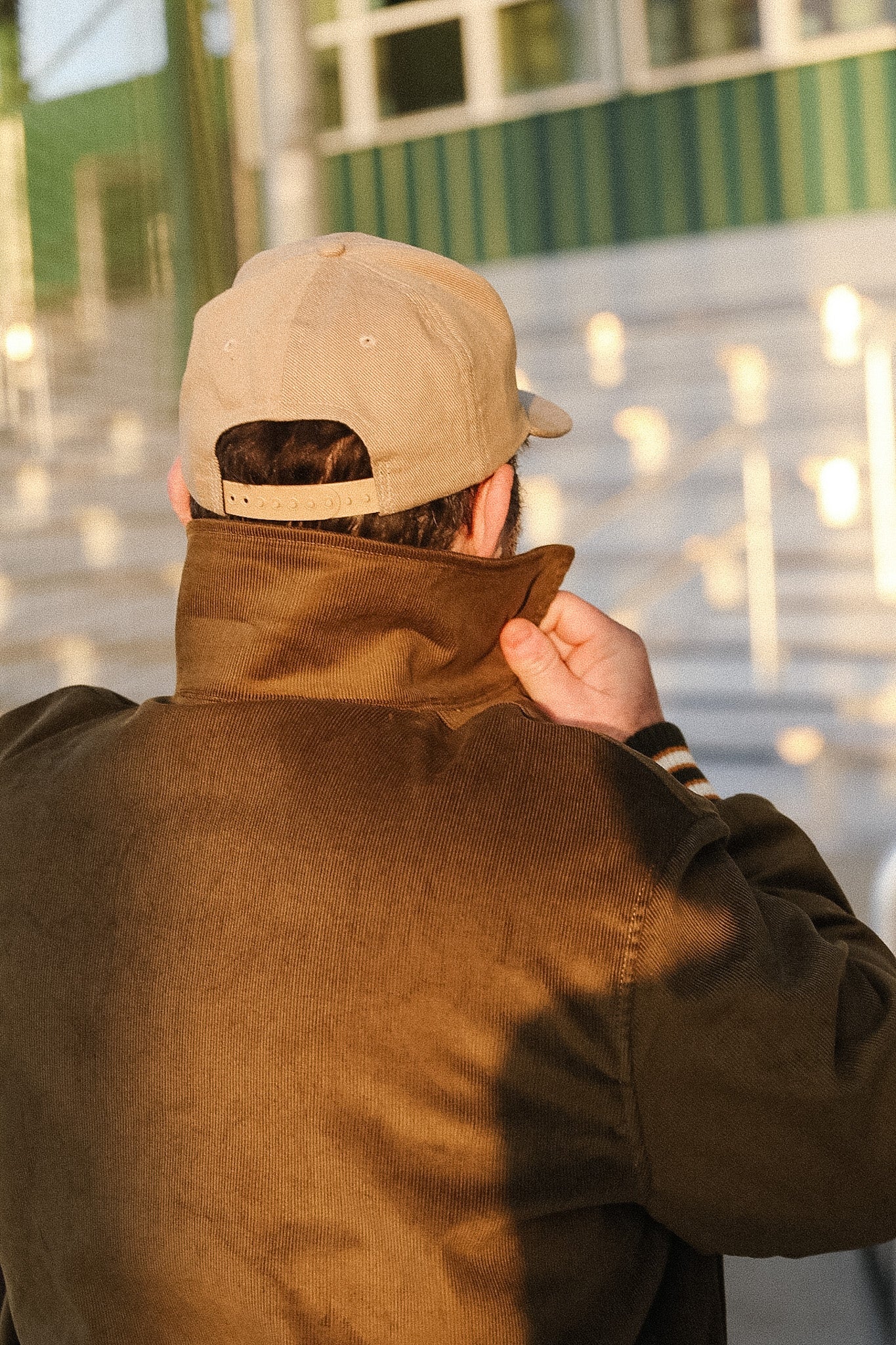 Person wearing a beige cap and brown jacket with a blurred background