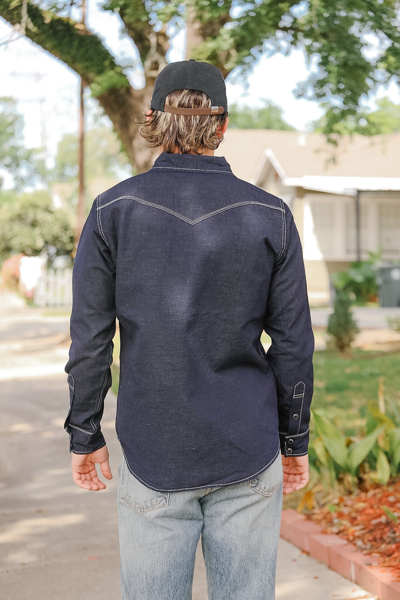 Person wearing a dark blue long-sleeve shirt with white stitching outdoors.