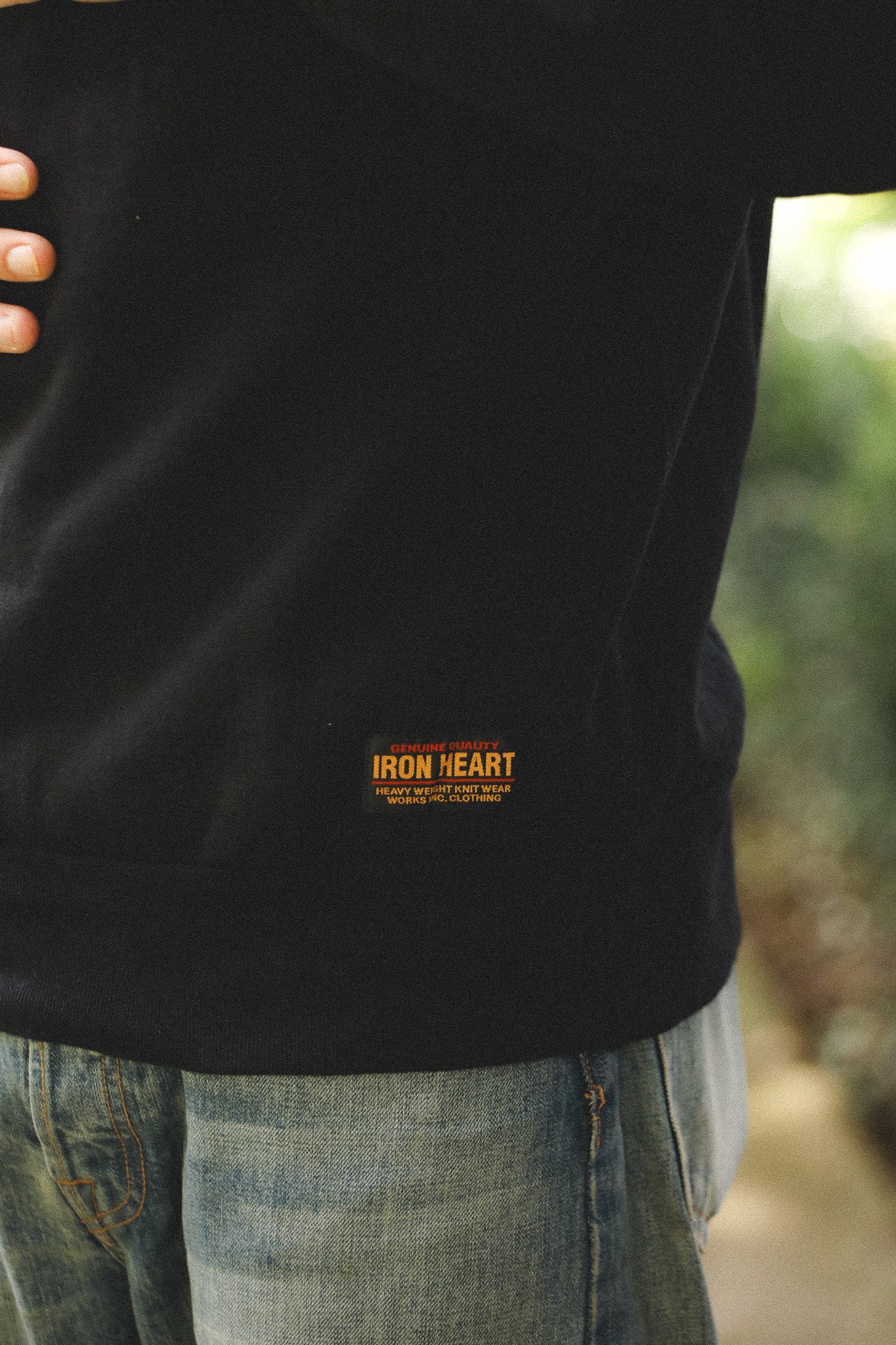 Person wearing a black jacket with 'Iron Heart' logo, blurred background