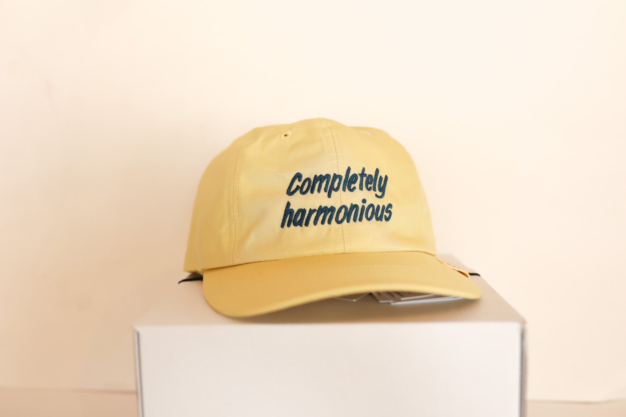 Yellow cap with 'Completely harmonious' text on a white box against a beige background