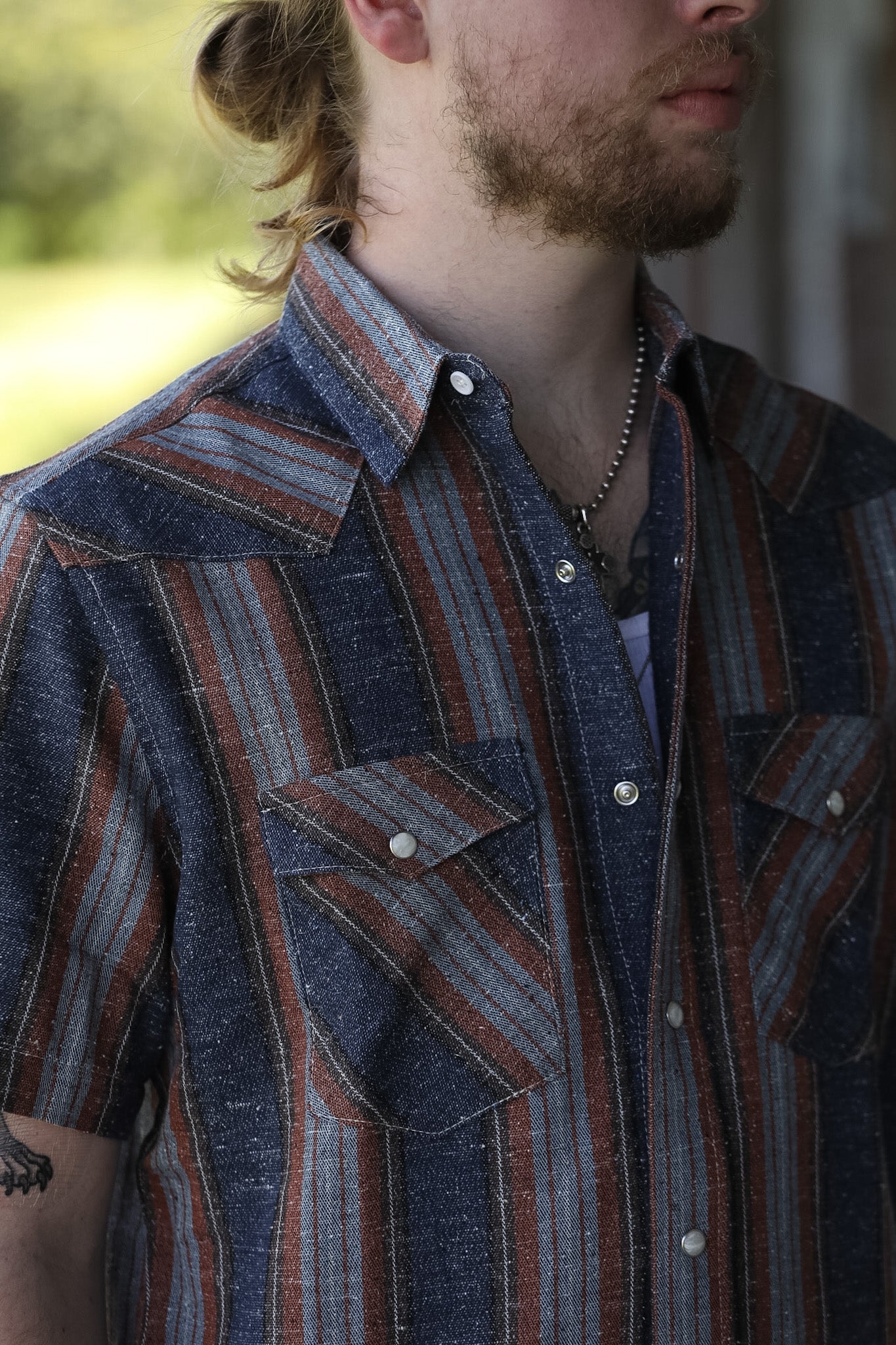 man wearing a stripe shirt standing in an industrial setting 