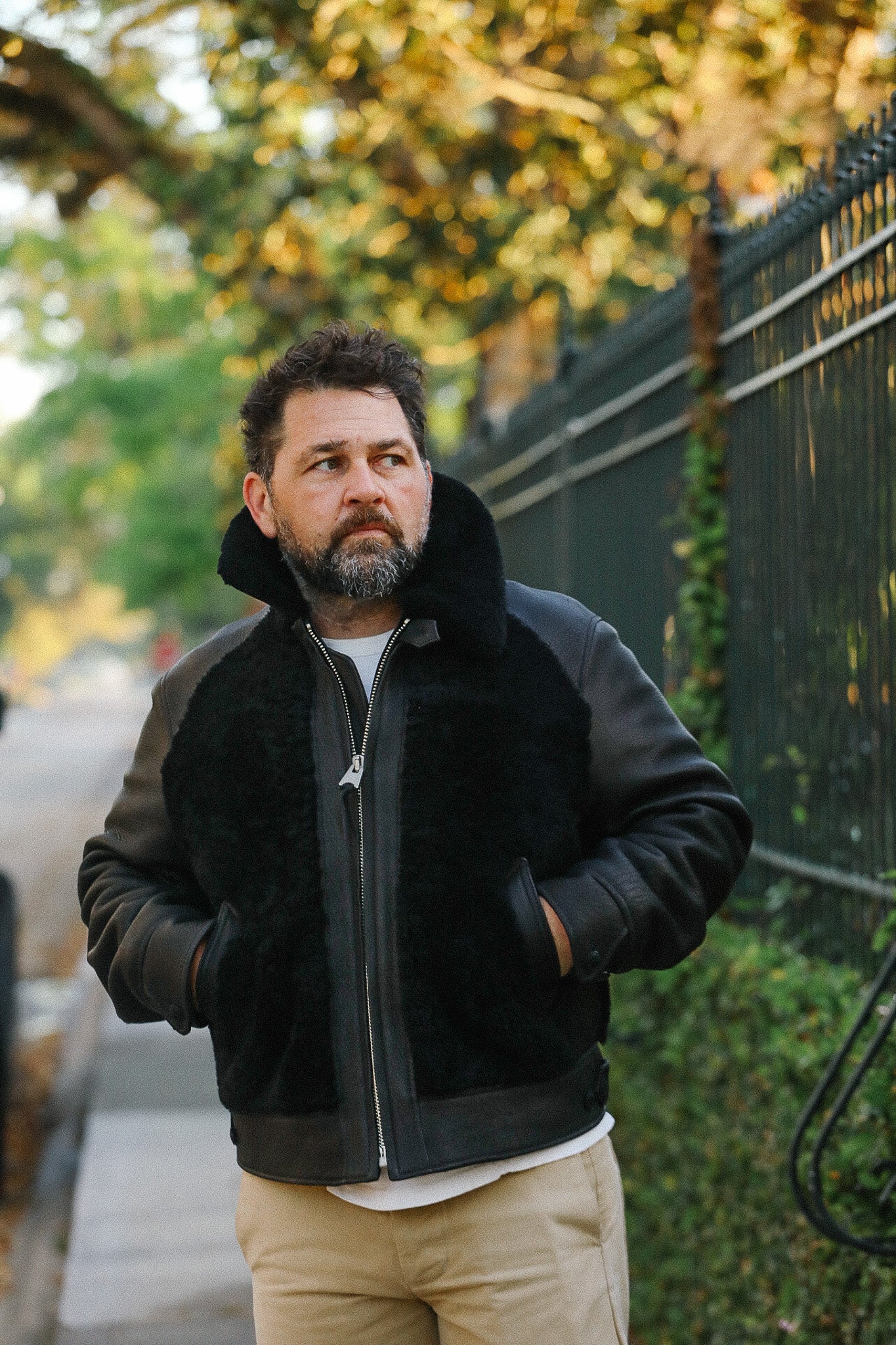 Man wearing a black jacket with a fur-lined hood outdoors