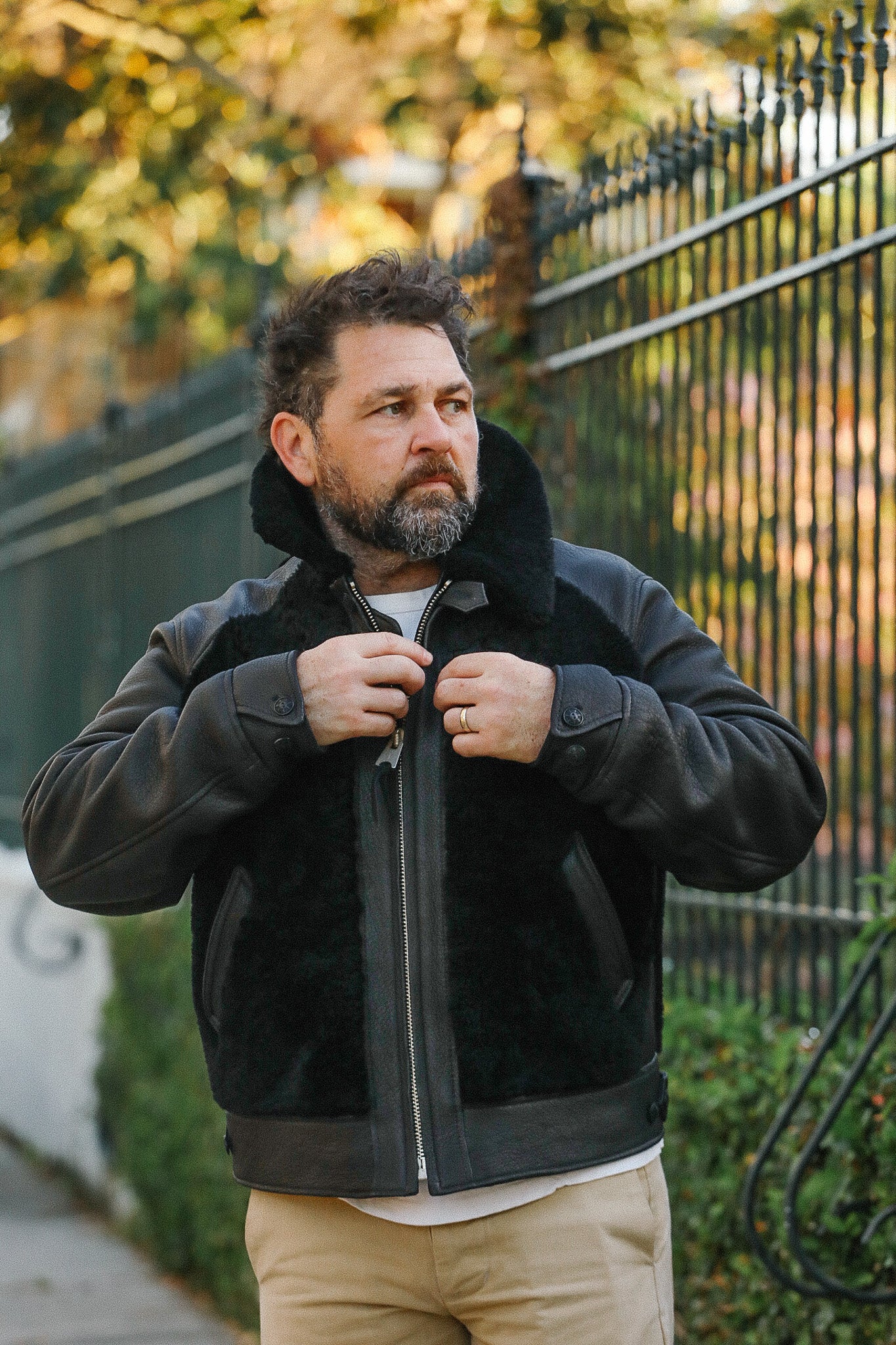 Man wearing a black shearling jacket outdoors with blurred background
