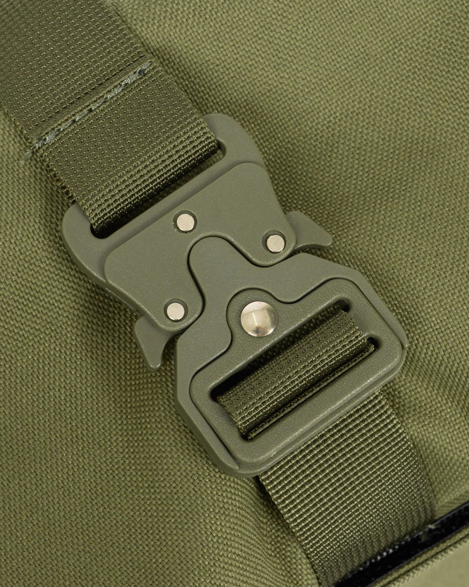 Close-up of an olive green nylon webbing strap with a matching dark gray plastic quick-release buckle on a bag.