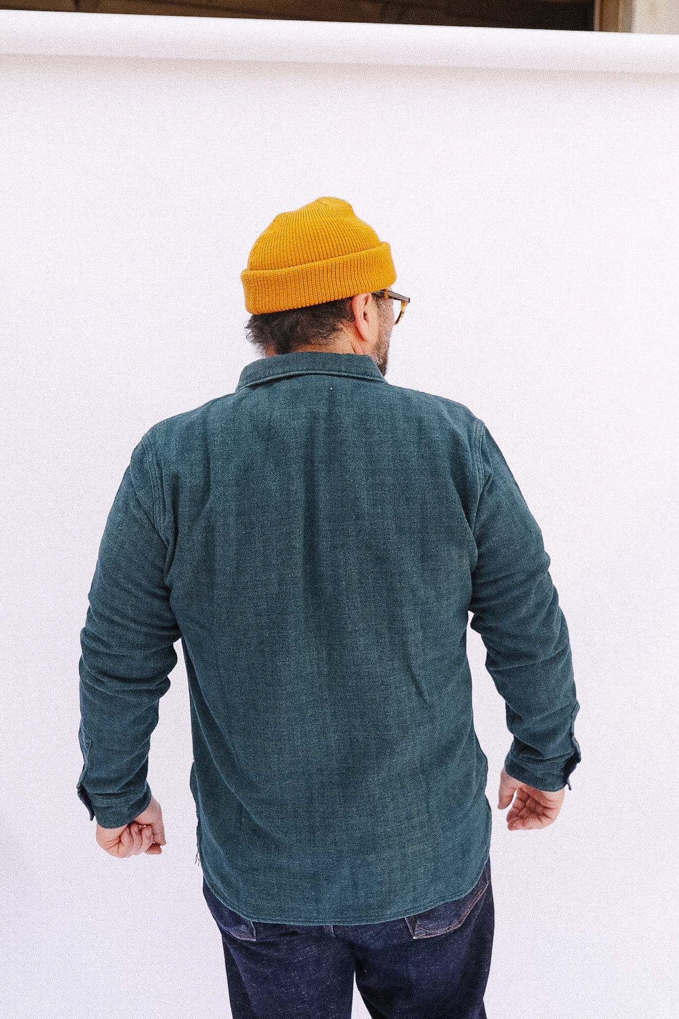Person wearing a yellow beanie and green shirt against a white background