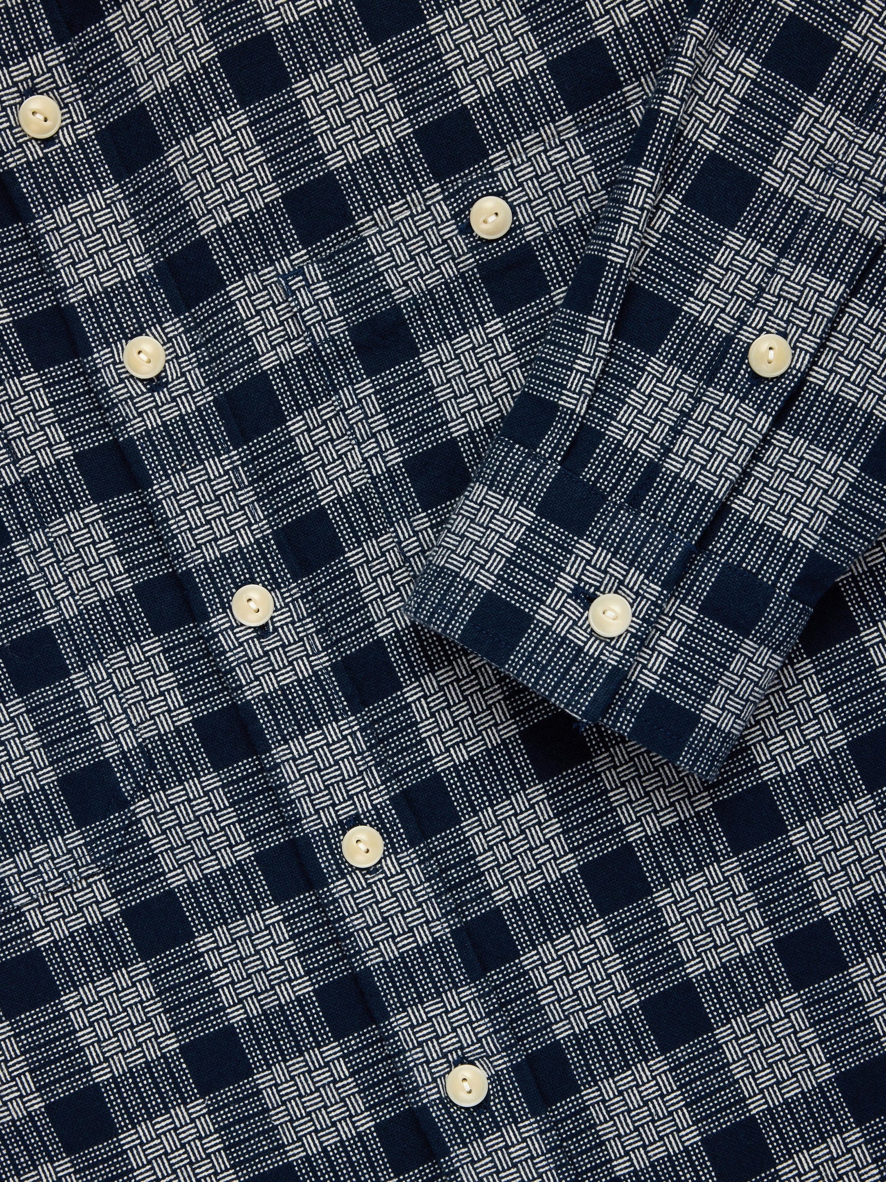 Close-up of a navy and white plaid button-down shirt with cream-colored buttons.