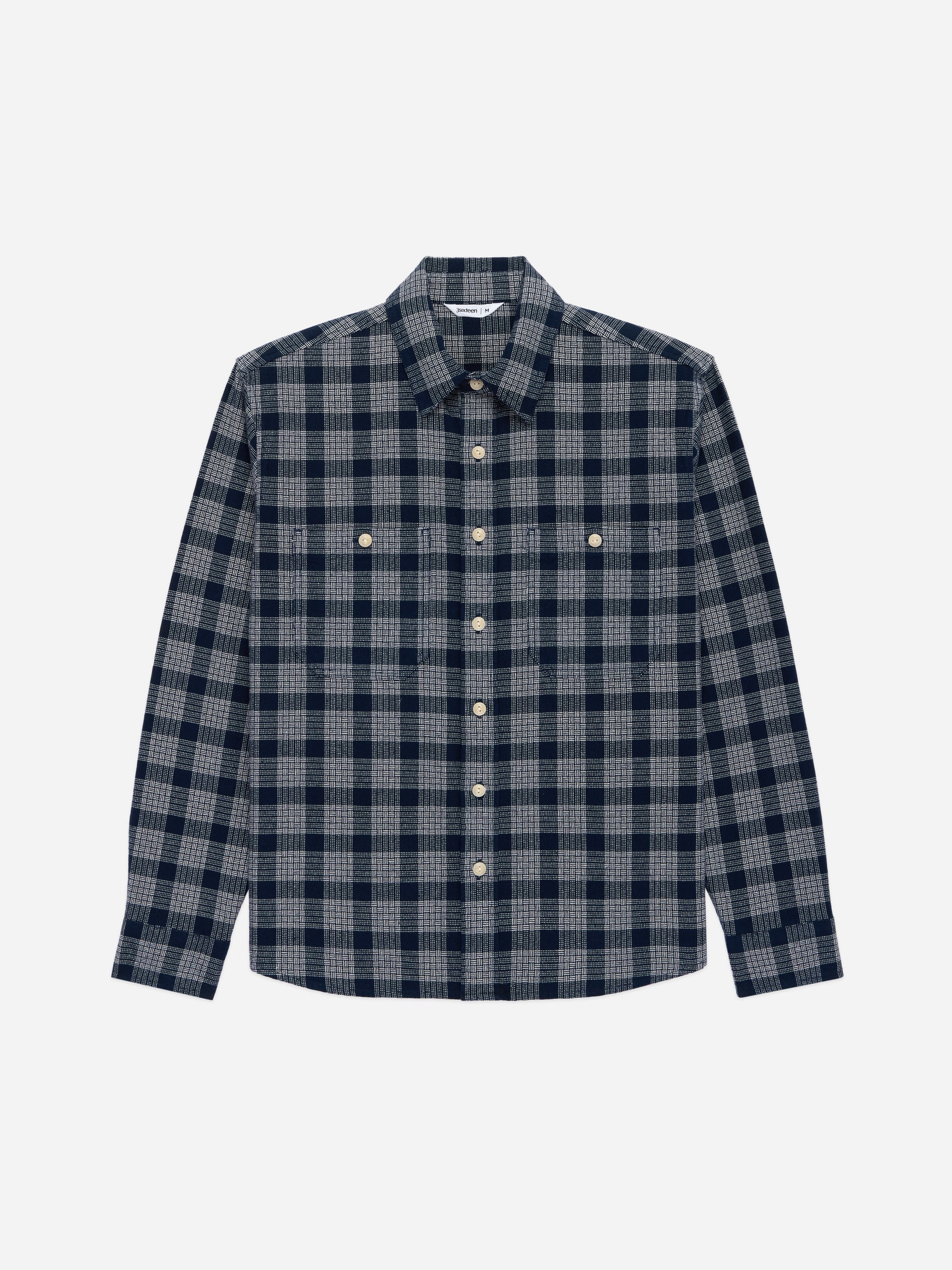 A long-sleeve button-up shirt with a navy and gray plaid pattern, featuring two buttoned chest pockets and a classic collar, shown against a light gray background.