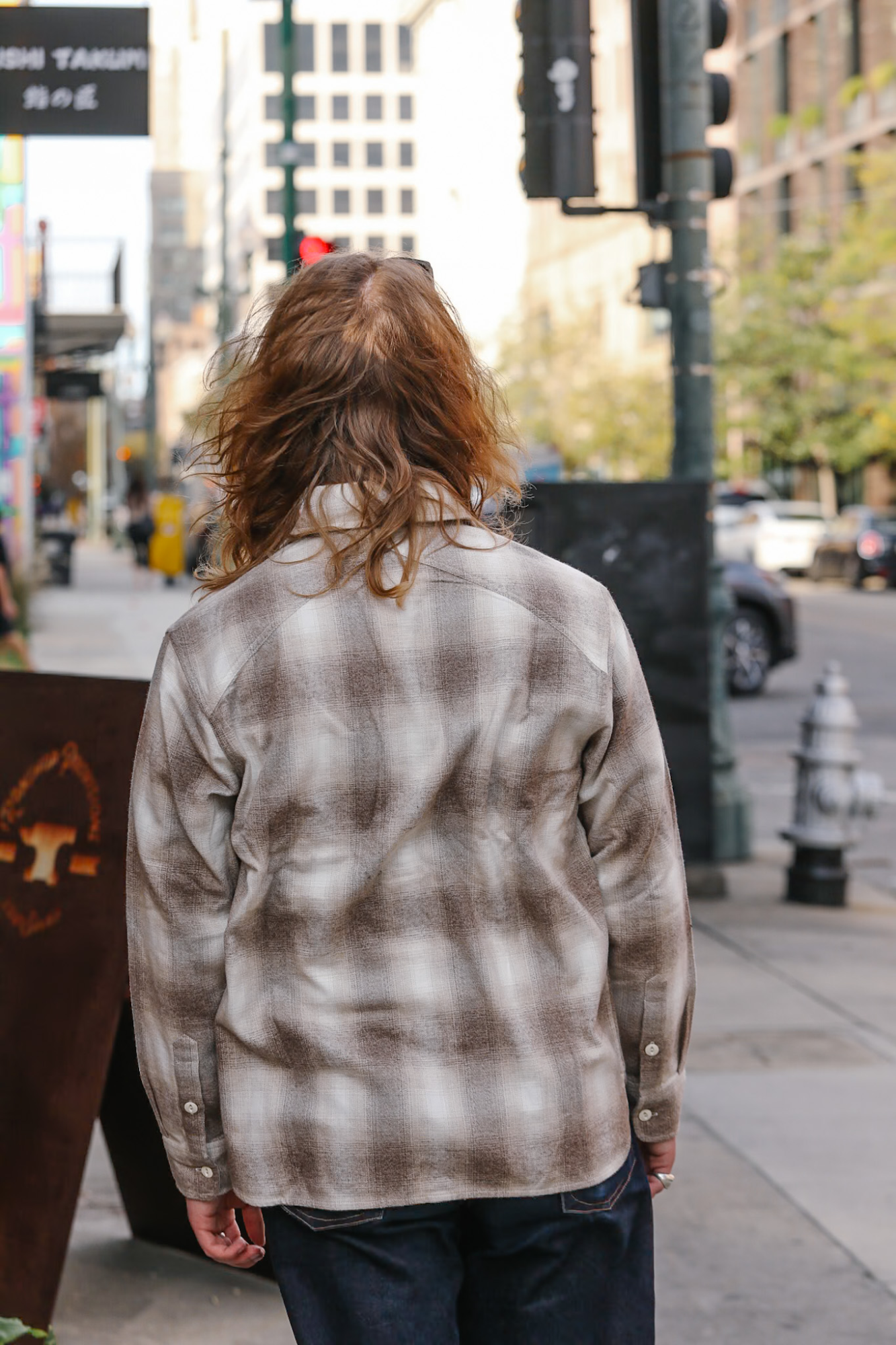 Person wearing a plaid shirt on a city street
