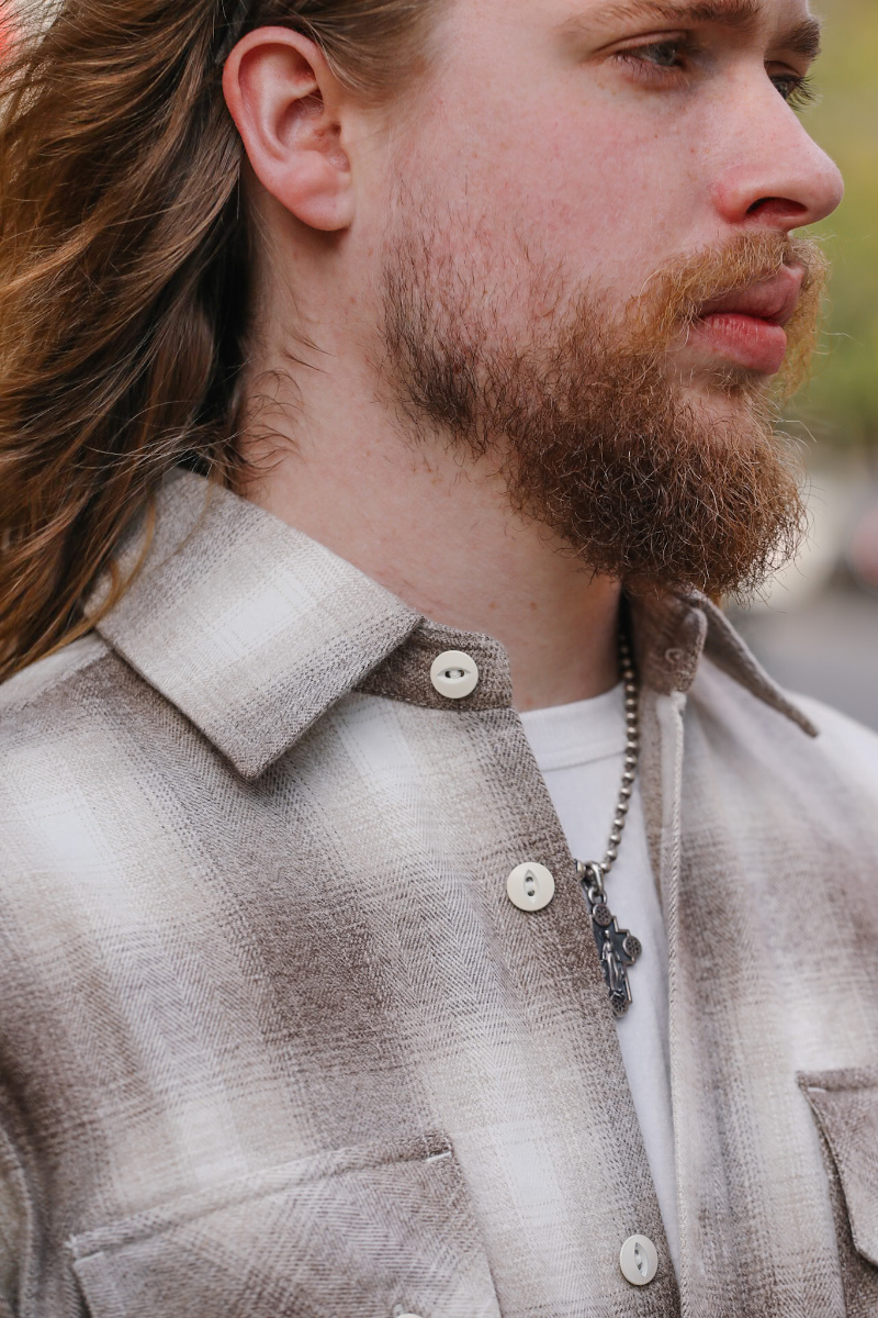 Man wearing a plaid shirt with a focus on the collar and buttons.