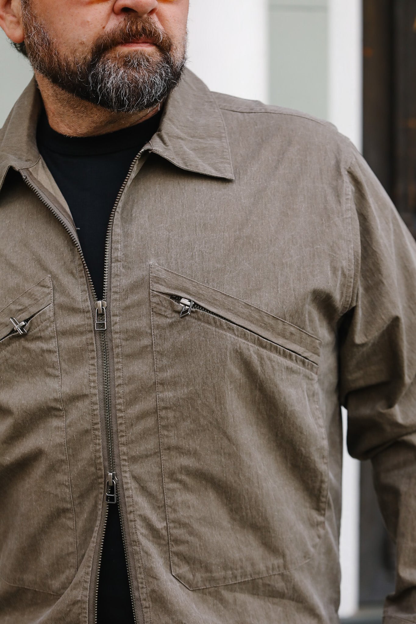 Man wearing a brown jacket with zippers on a blurred background