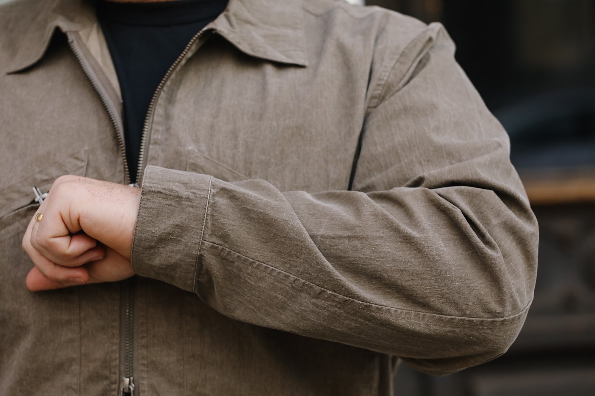 Close-up of a person wearing a brown jacket with a blurred background