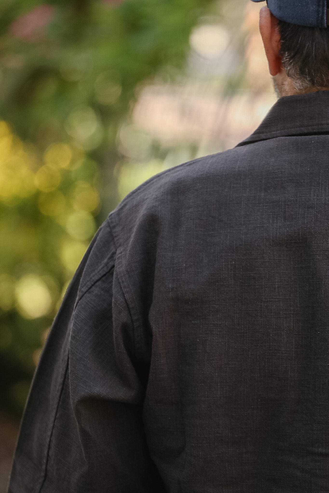 Person wearing a dark jacket with a blurred natural background