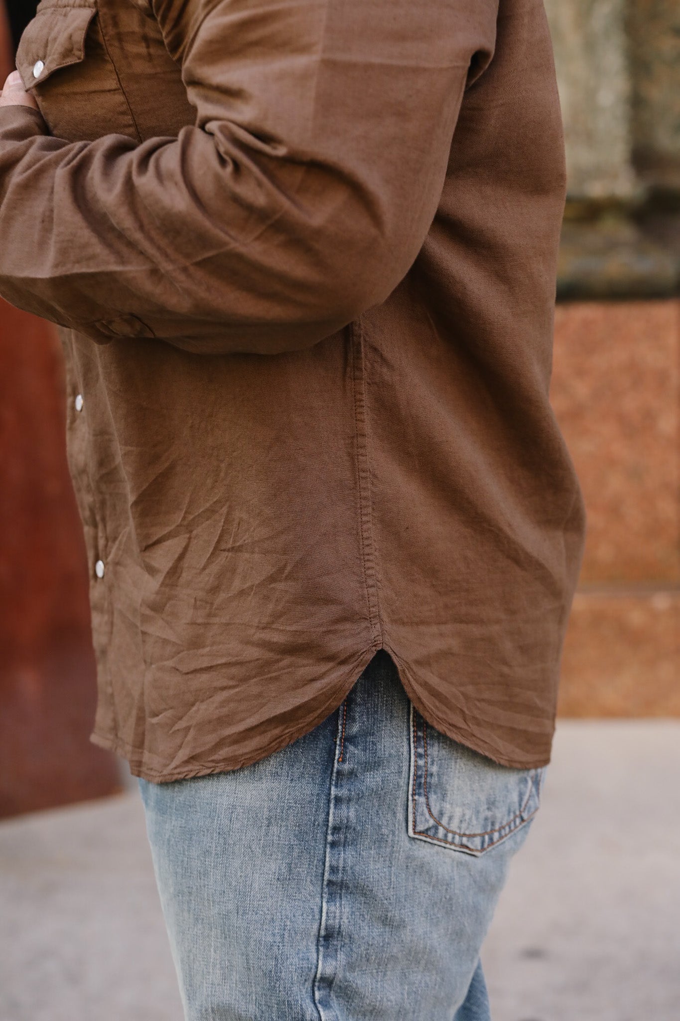 Brown jacket and blue jeans worn by a person against a blurred background
