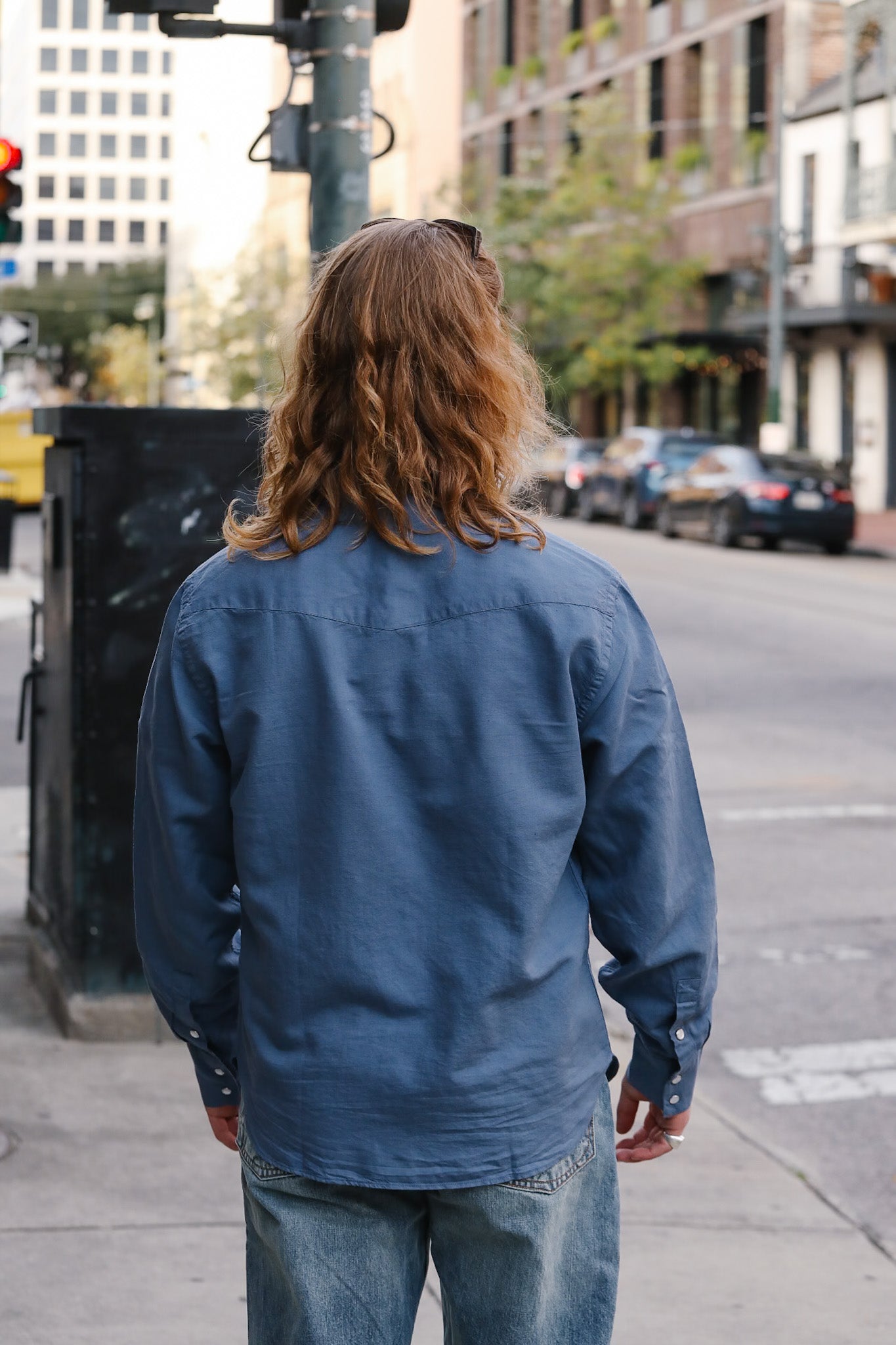 Person wearing a blue jacket walking on a city street