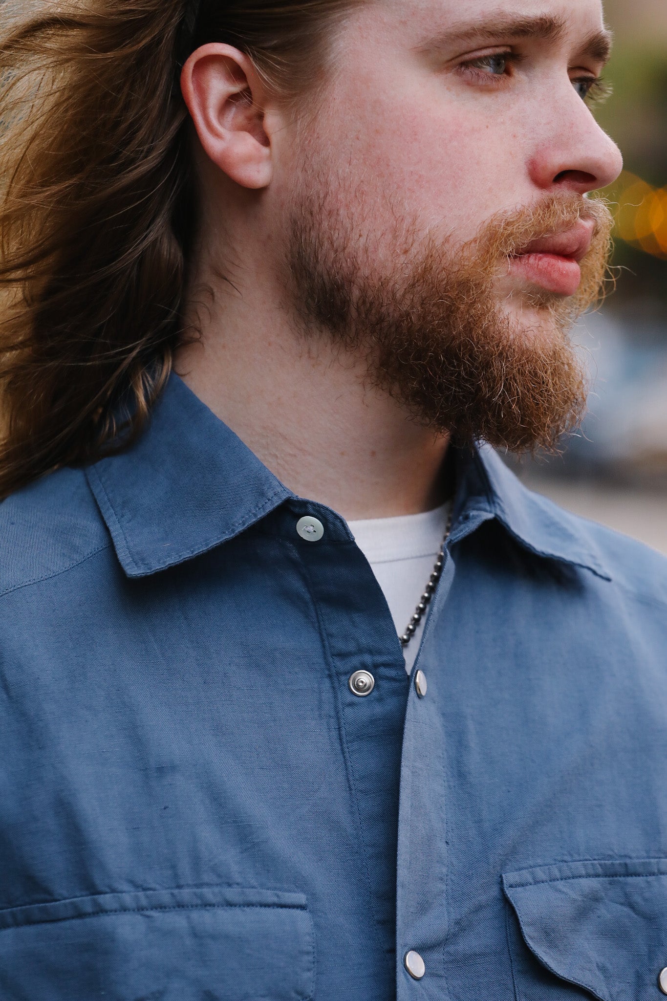 Man with a beard wearing a blue shirt outdoors