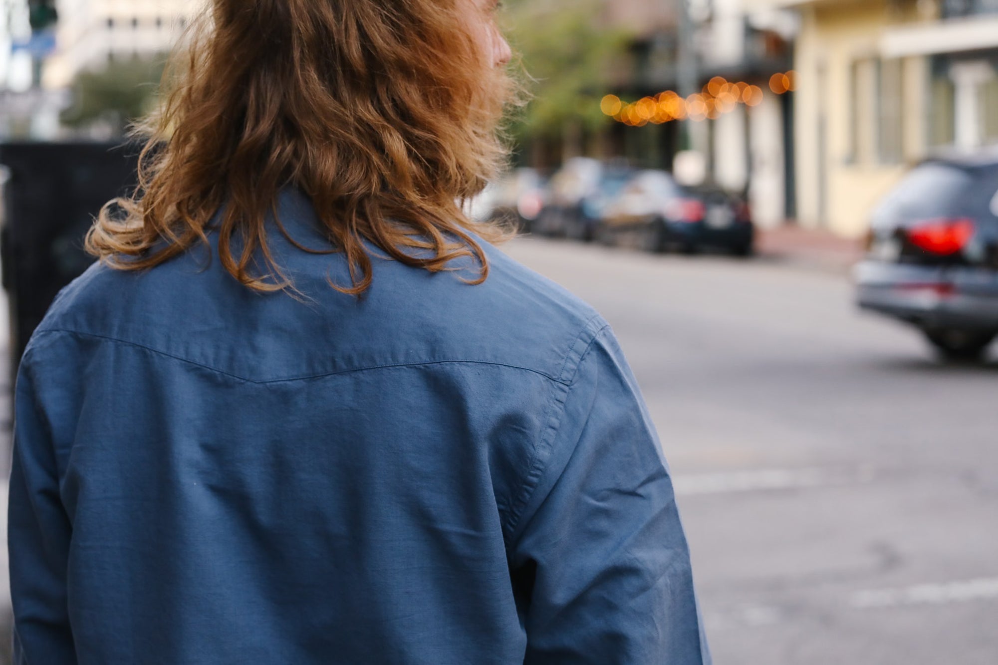 Person holding a white product packaging with text, wearing a gold chain and ring.