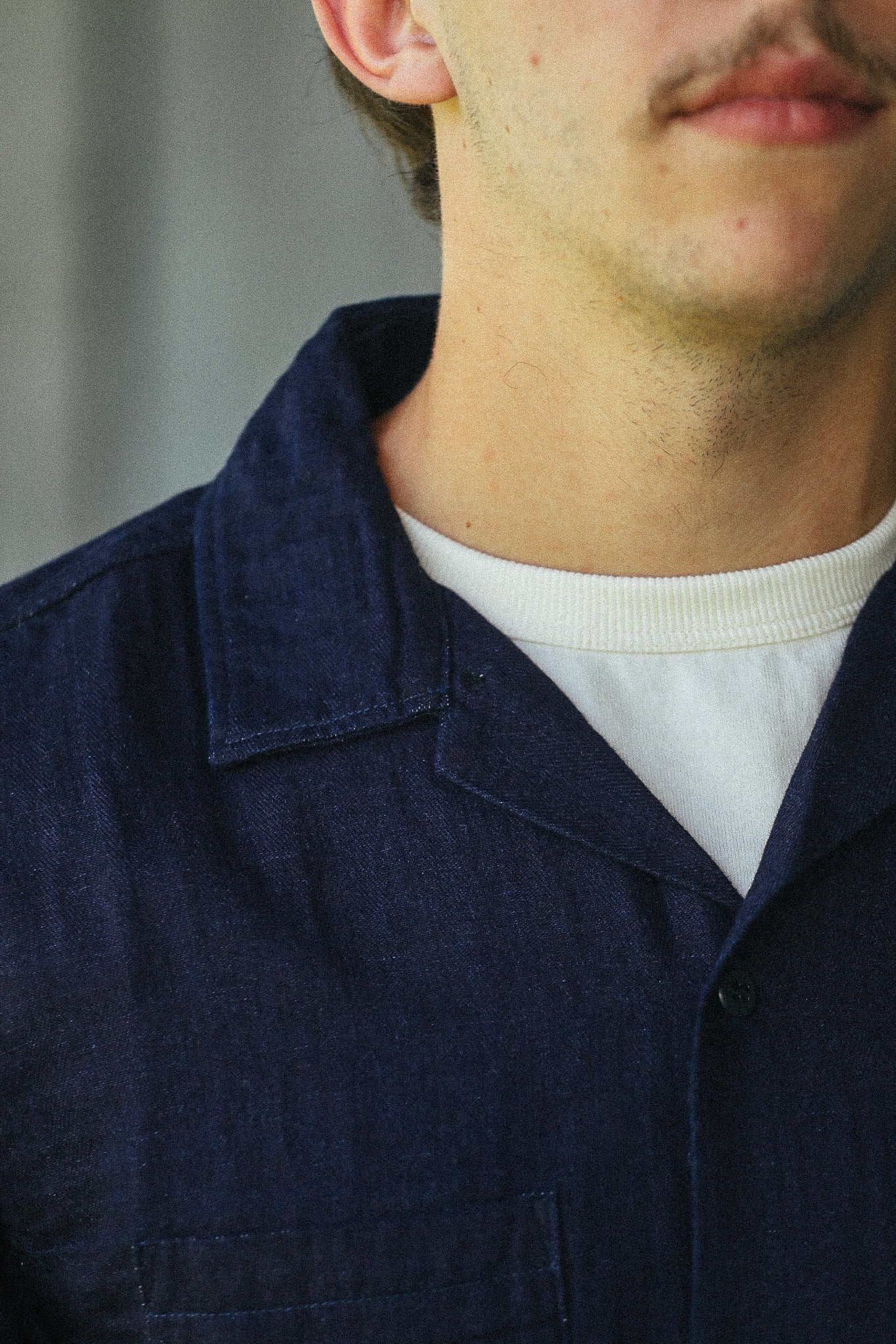 Close-up of a person wearing a dark navy textured overshirt over a white crewneck t-shirt.