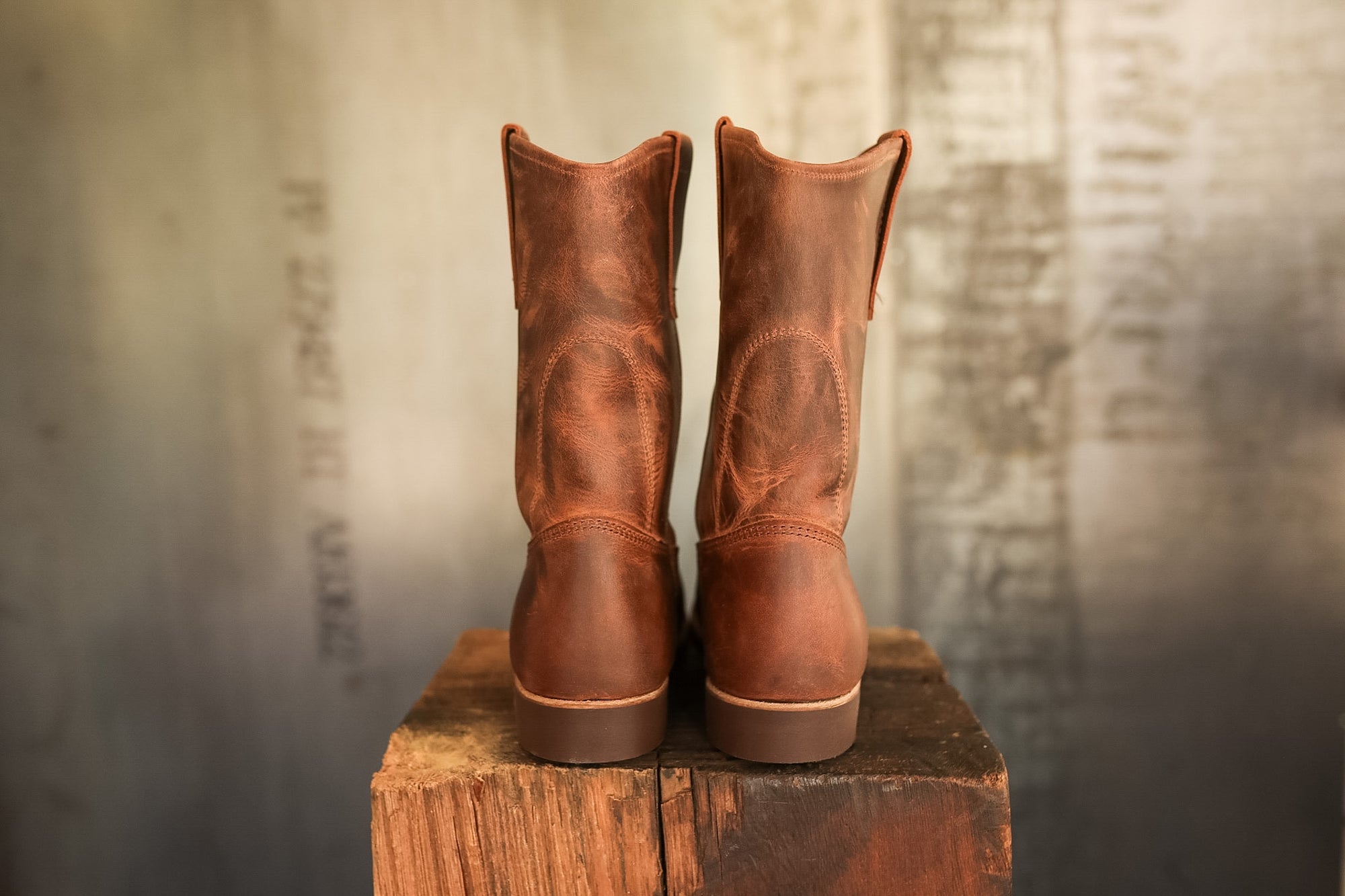 Pair of brown leather boots on a wooden block with a rustic background