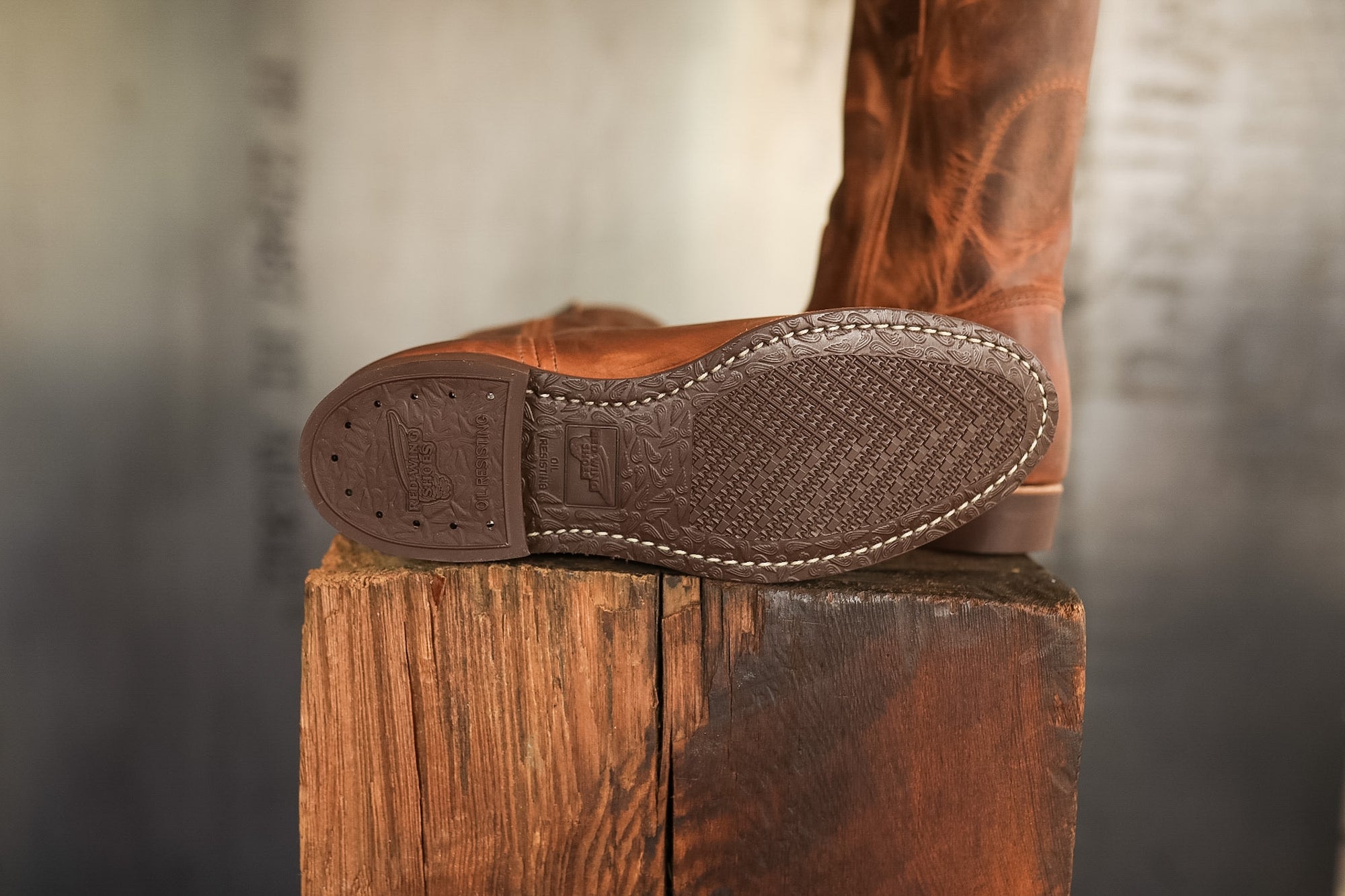 Brown cowboy boot on a wooden block with a blurred background