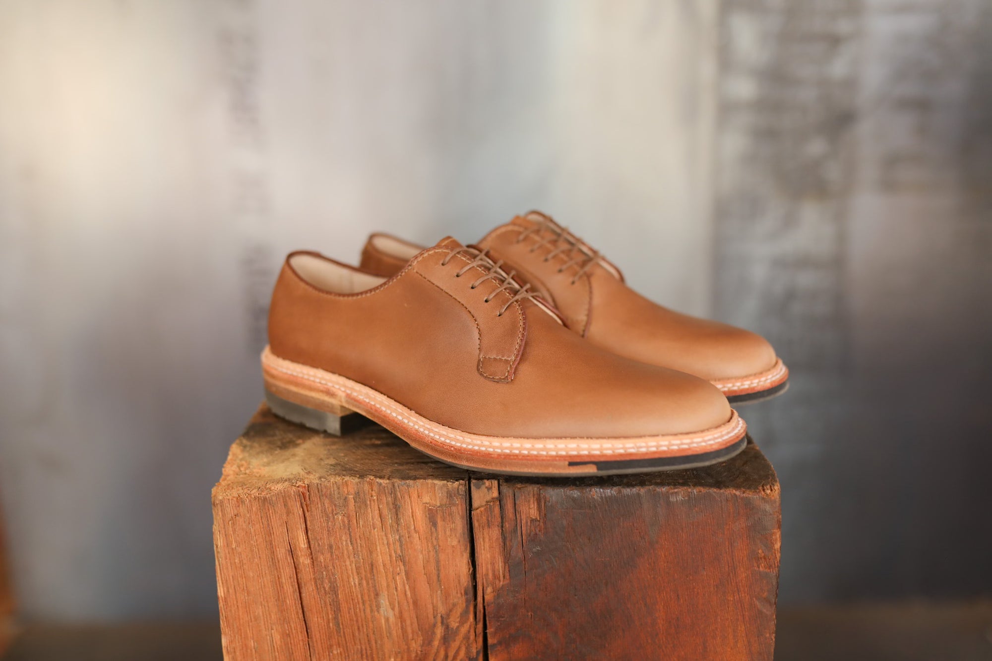 Pair of brown leather shoes on a wooden block with a blurred background