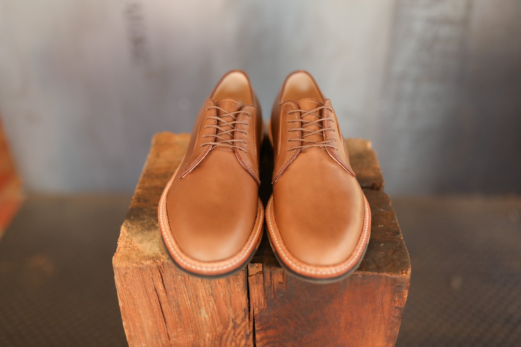 Pair of brown leather shoes on a wooden block with a blurred background