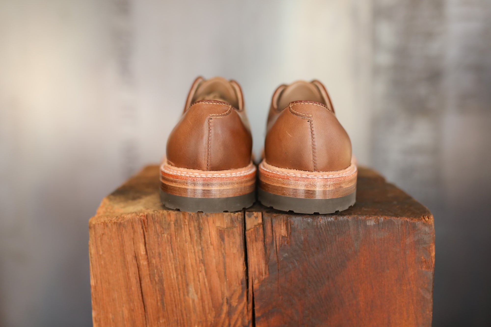 Pair of brown leather shoes on a wooden block with a blurred background