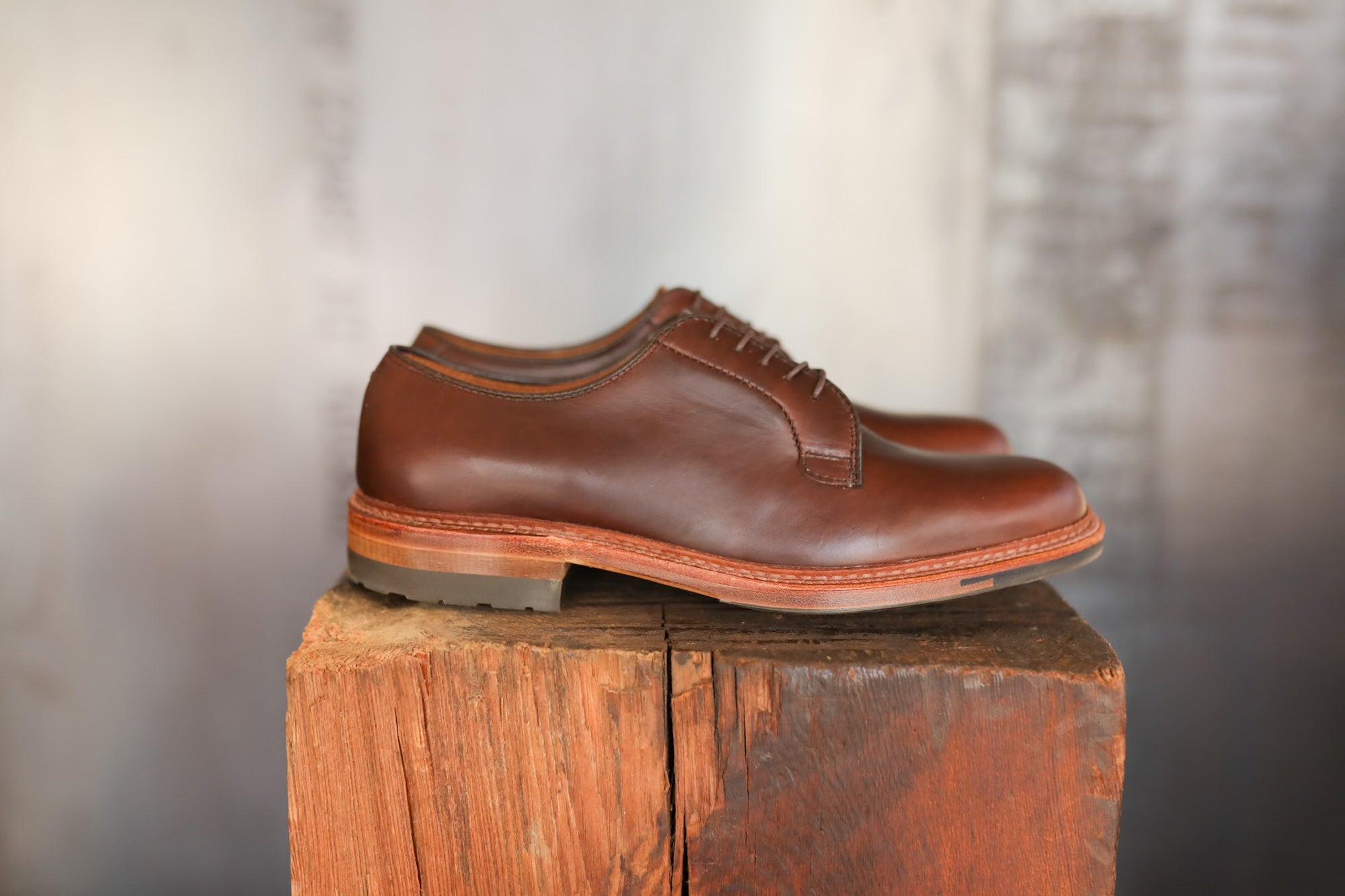 Pair of brown leather shoes on a wooden block with a neutral background