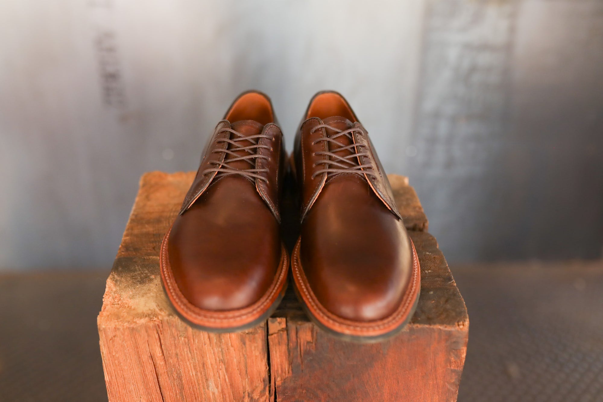 Pair of brown leather shoes on a wooden block with a blurred background