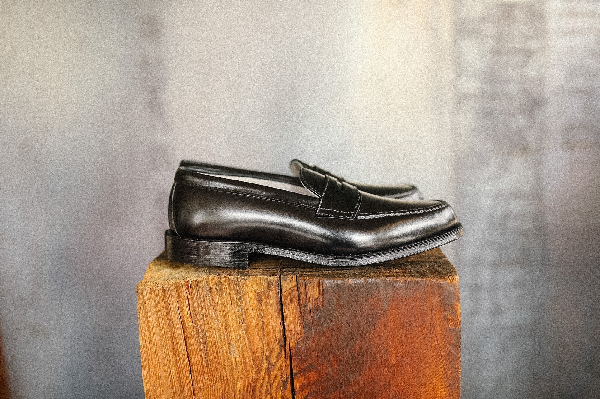 Pair of black loafers on a wooden block with a blurred background