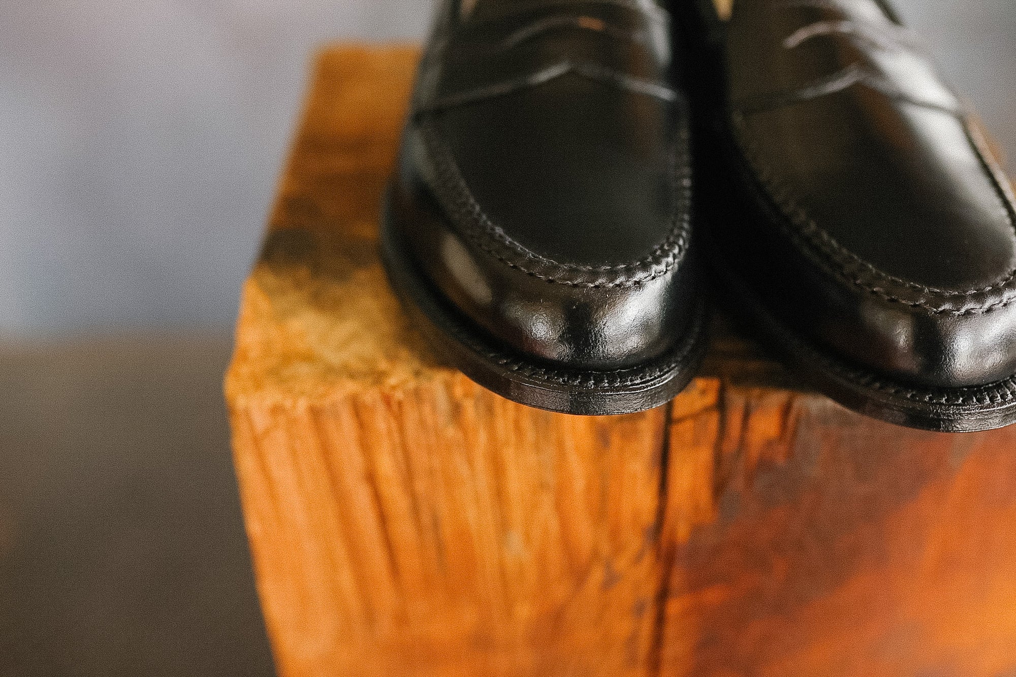 Pair of black leather shoes on a wooden block with a blurred background