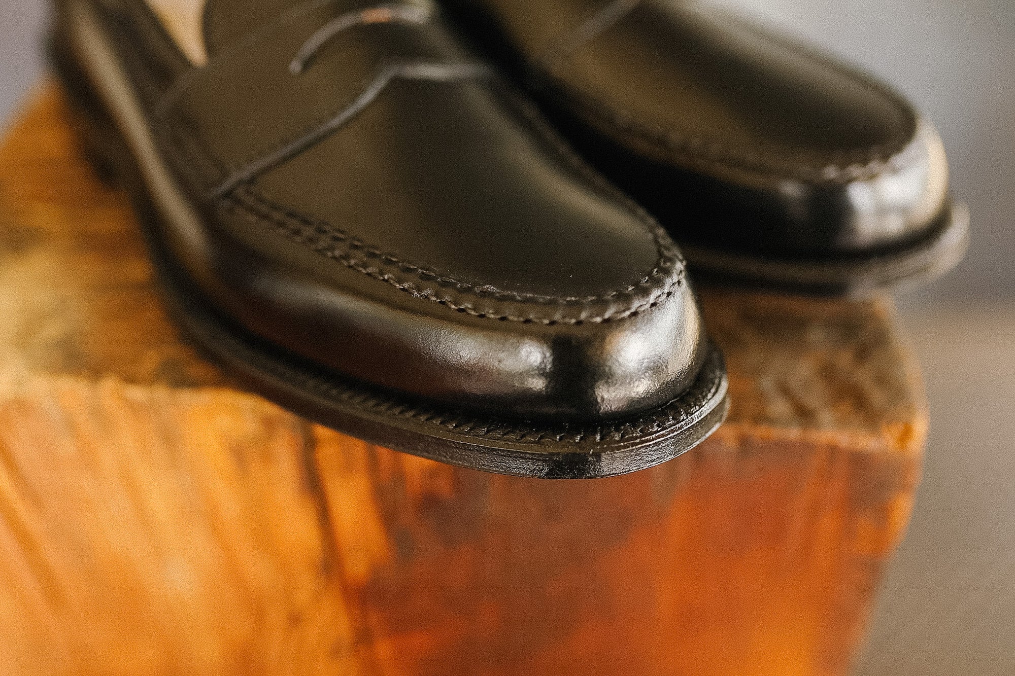 Pair of black leather shoes on a wooden surface with a blurred background