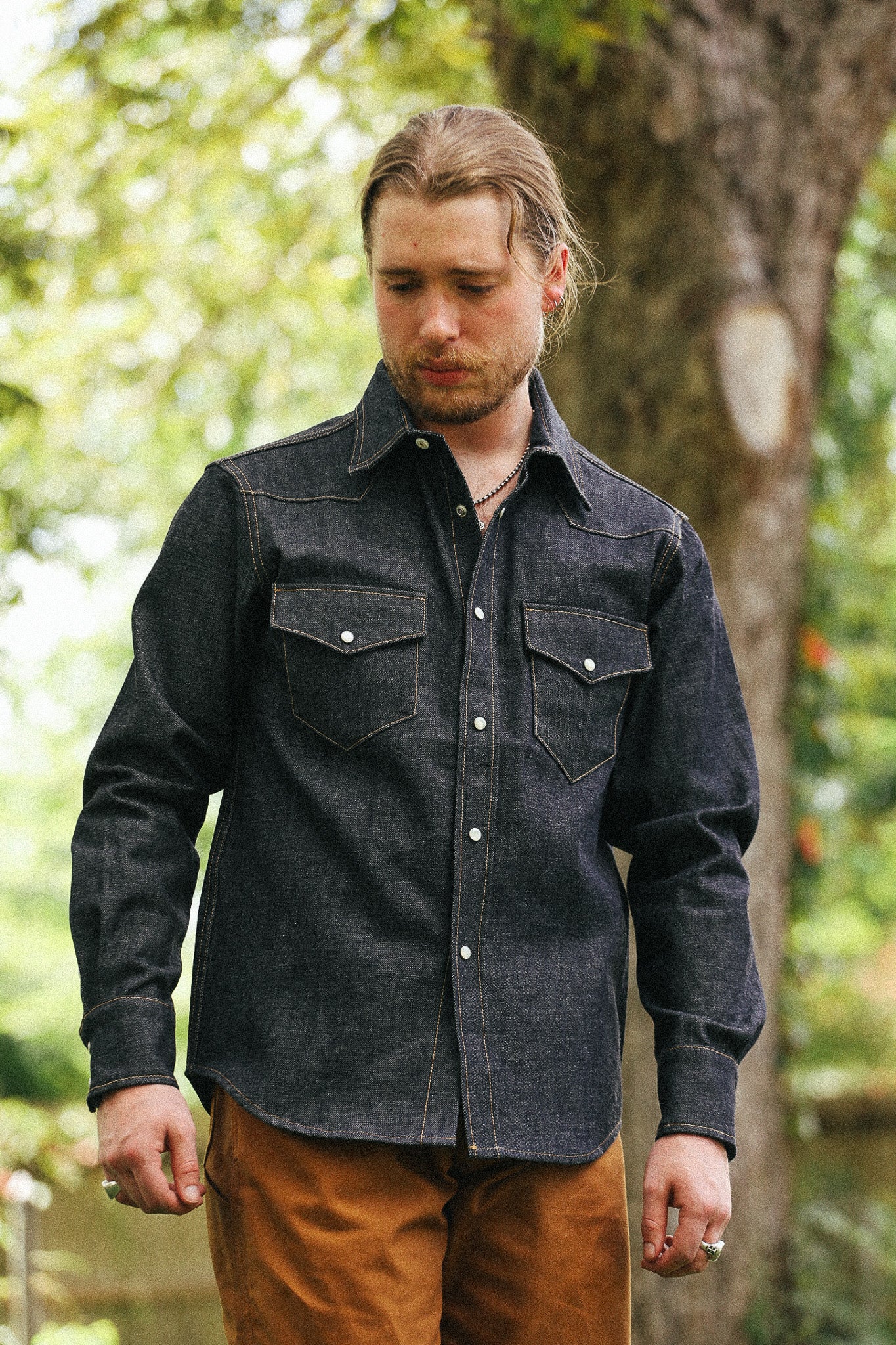 man with denim shirt against a green natural background