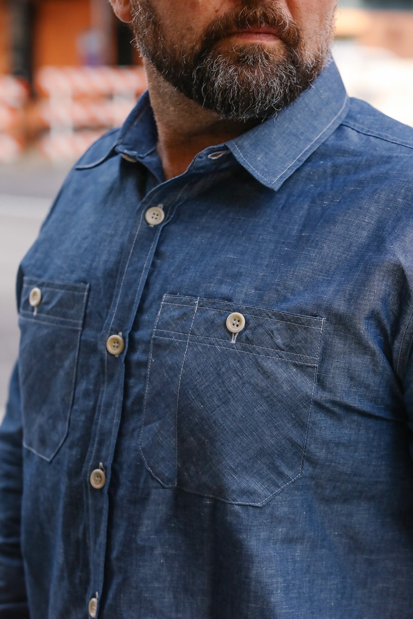 Close-up of a person wearing a blue denim shirt with a blurred background