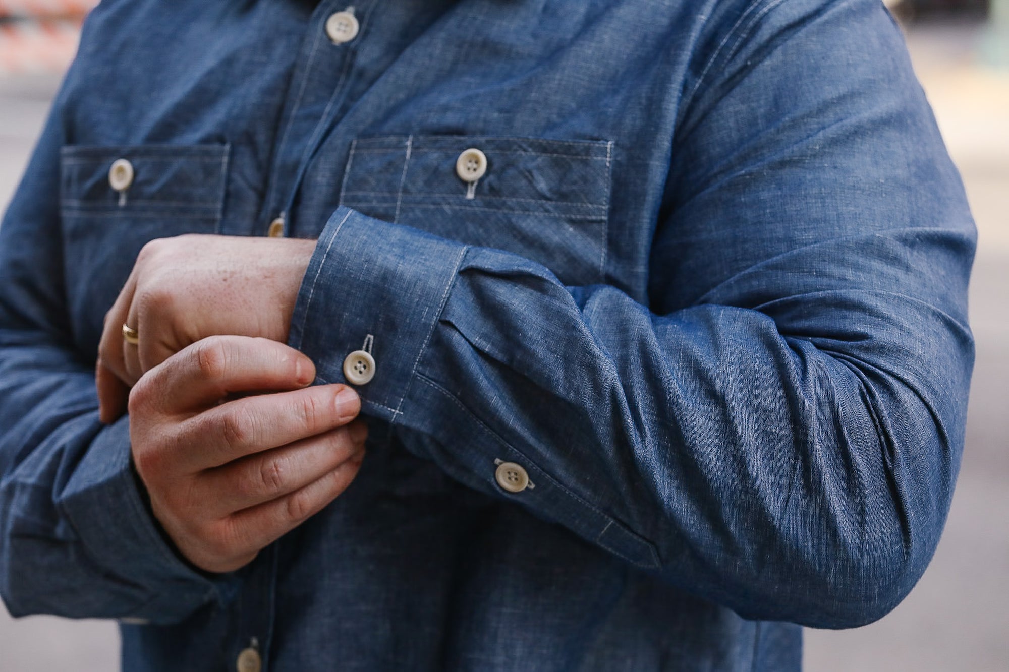 Person wearing a blue denim shirt with rolled-up sleeves.