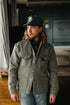 Man wearing a green jacket and black cap indoors