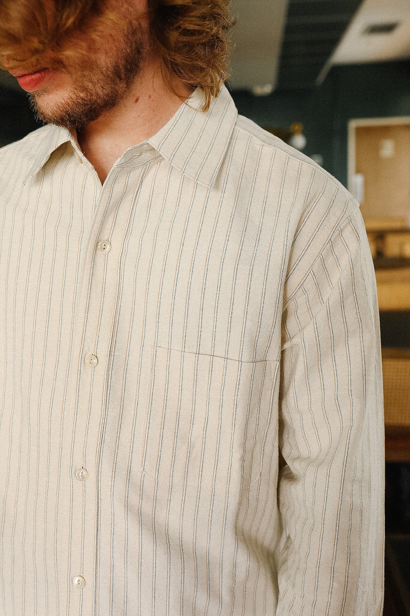 Close-up of a person wearing a light-colored striped shirt indoors.