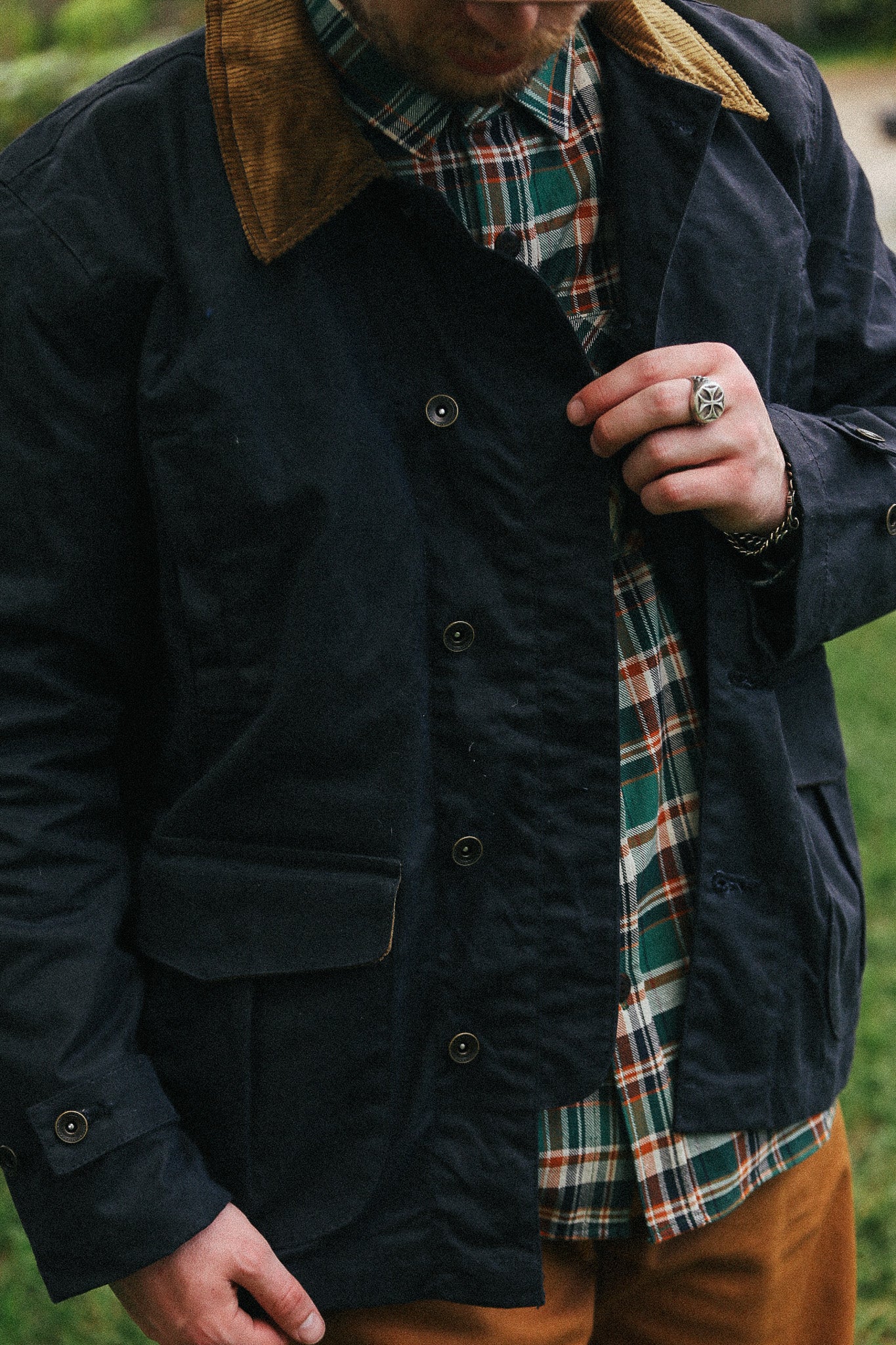 man with black jacket with showing front detail against a green natural background