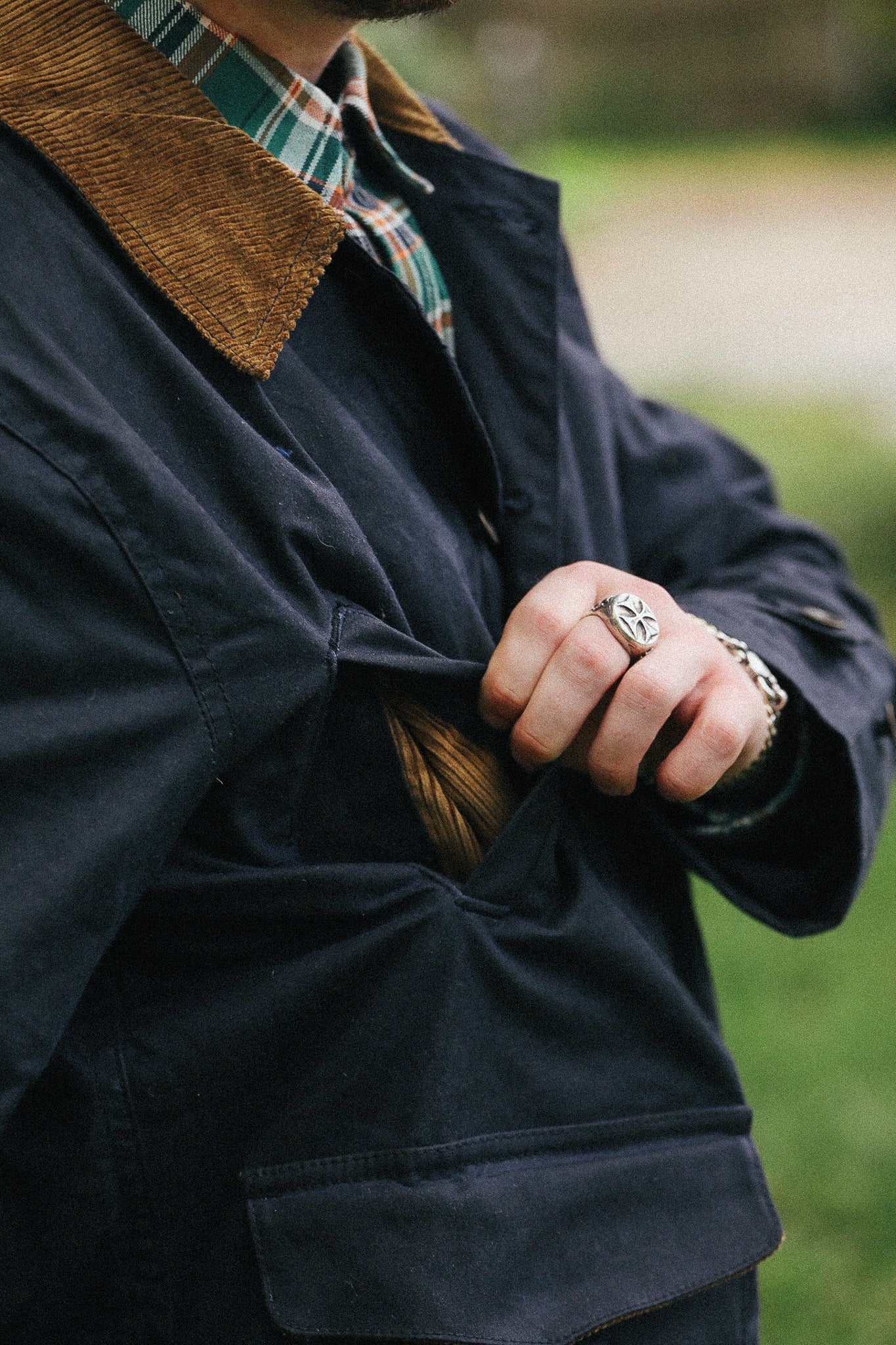 man with black jacket with showing pocket detail against a green natural background