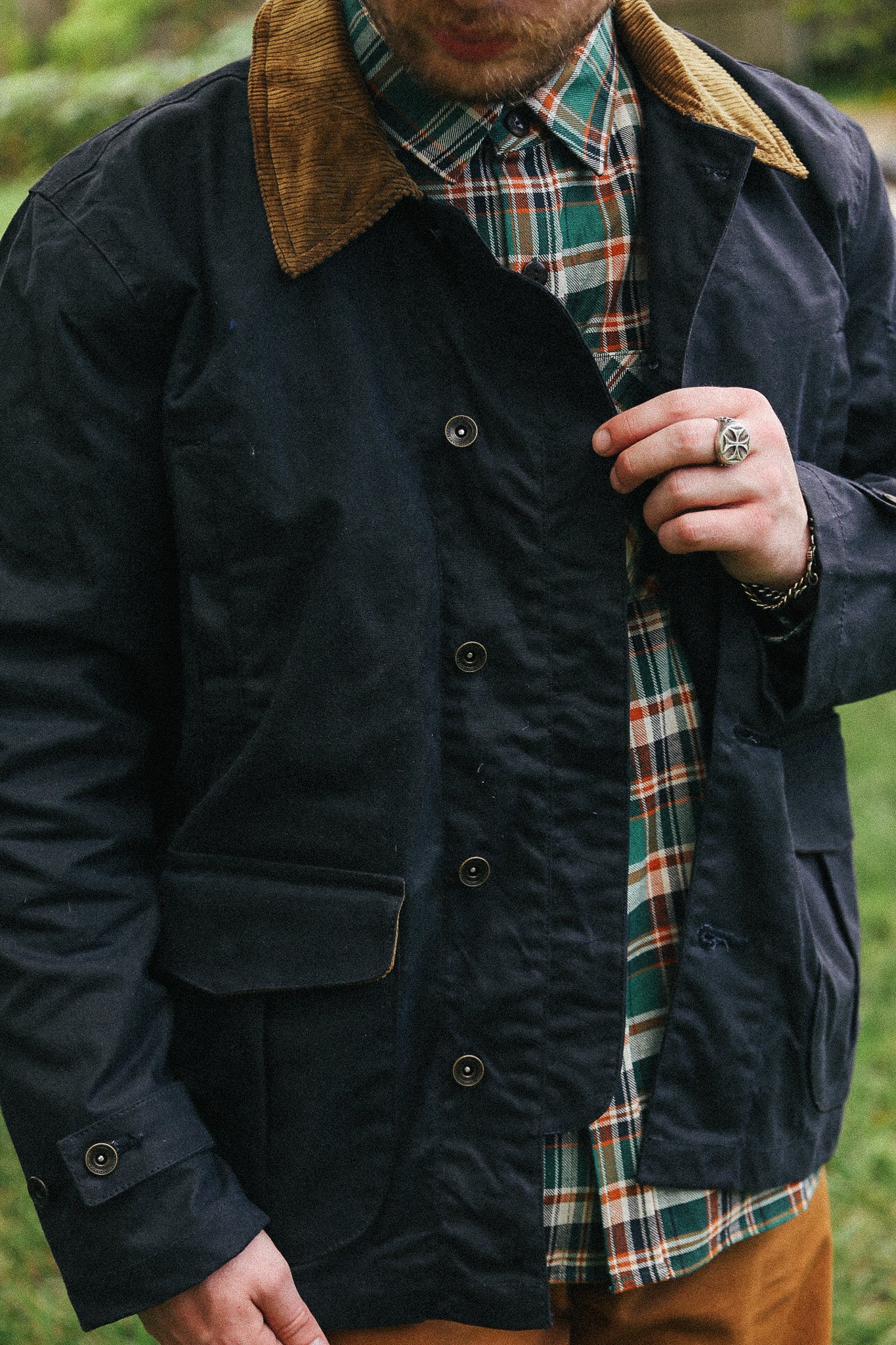 man with black jacket with showing  detail against a green natural background
