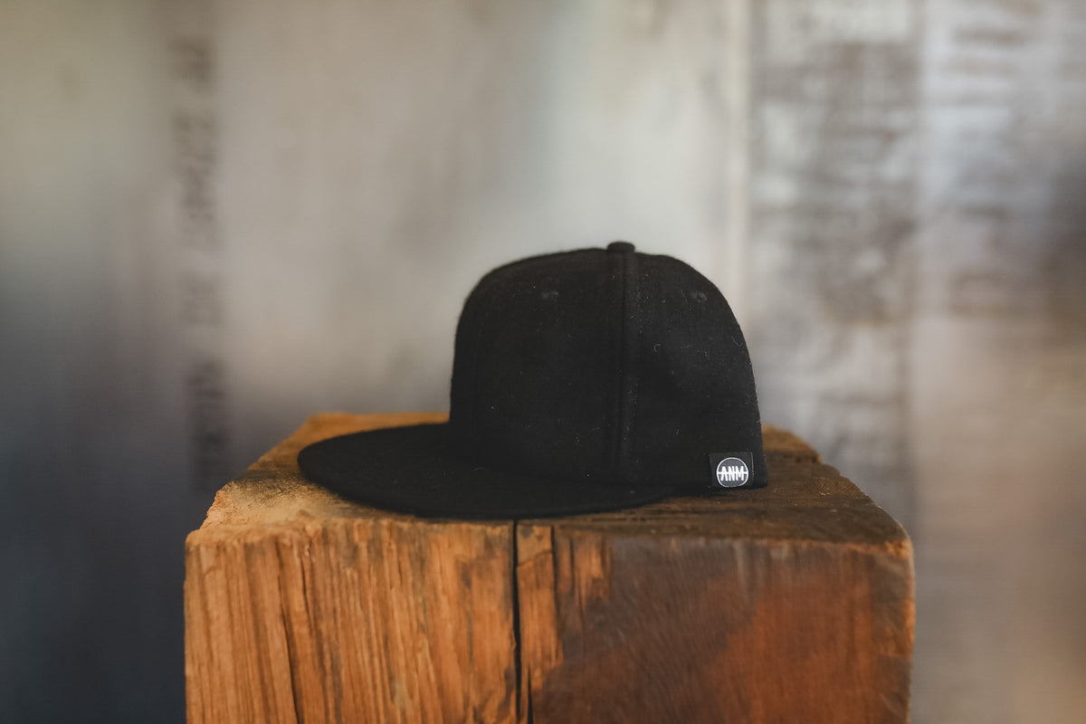 Up close of a black baseball cap on wood block 