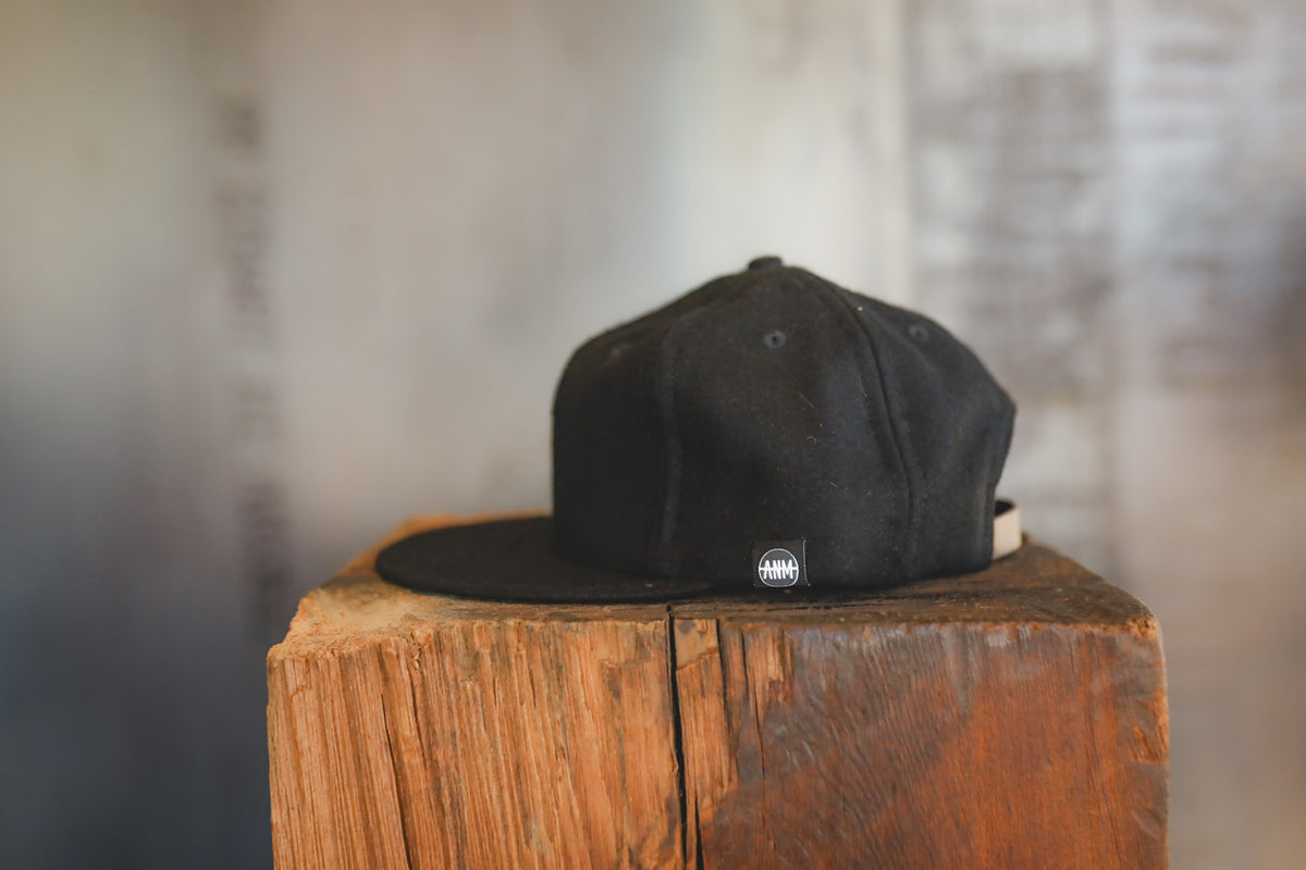 Up close of a black baseball cap on wood block 