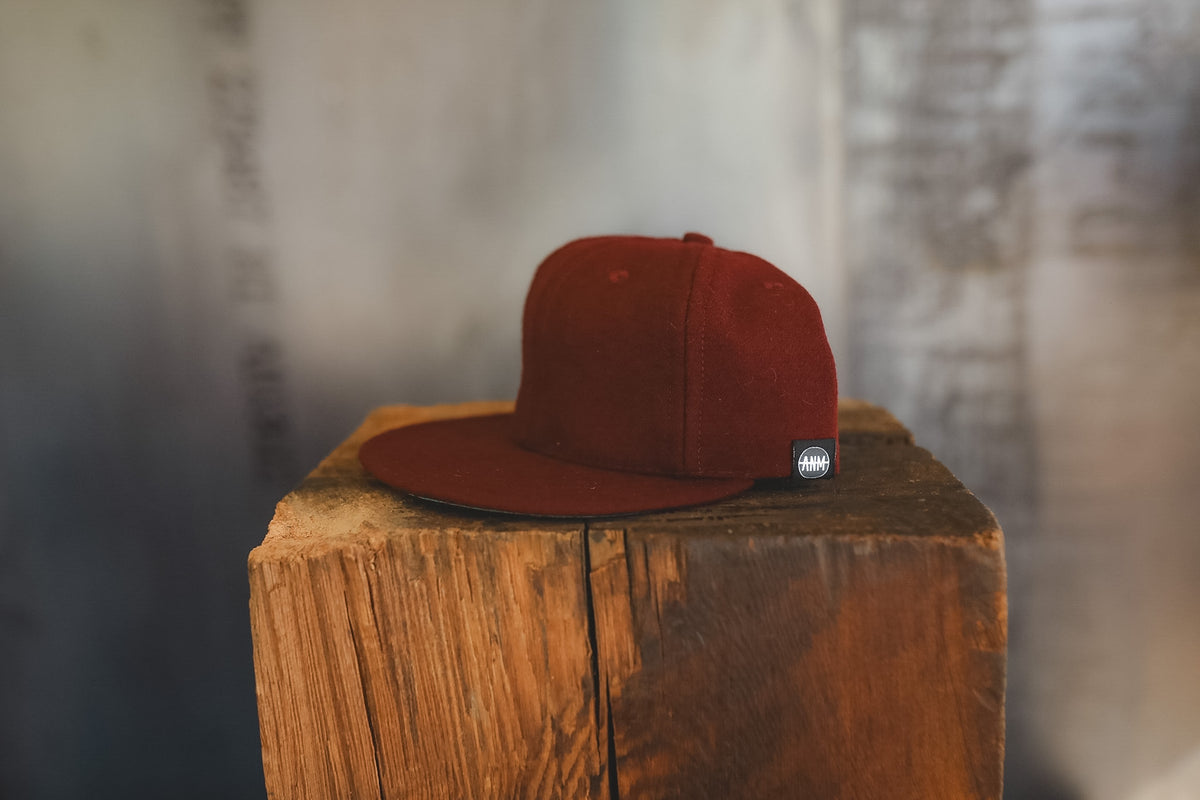 Dark maroon baseball cap on a wood block 