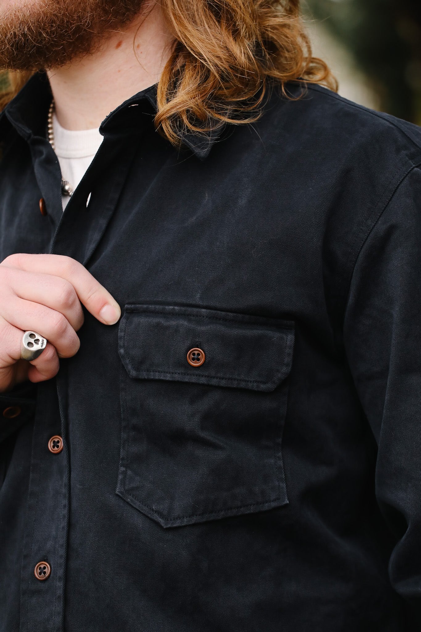 Person wearing a dark blue shirt with a pocket and buttons.