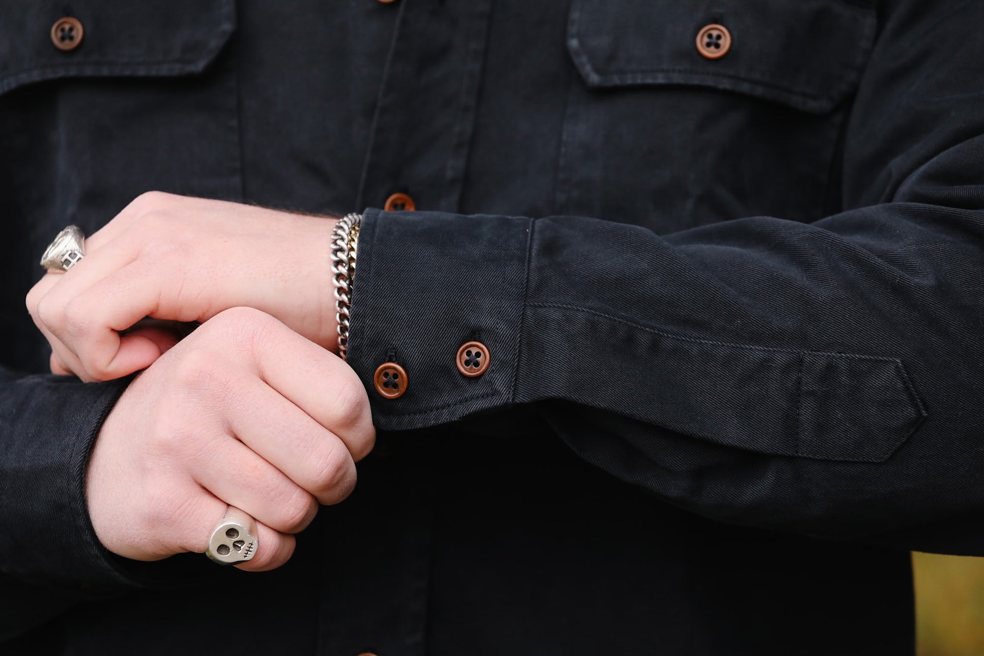 Close-up of a person wearing a dark jacket with visible buttons and a bracelet.