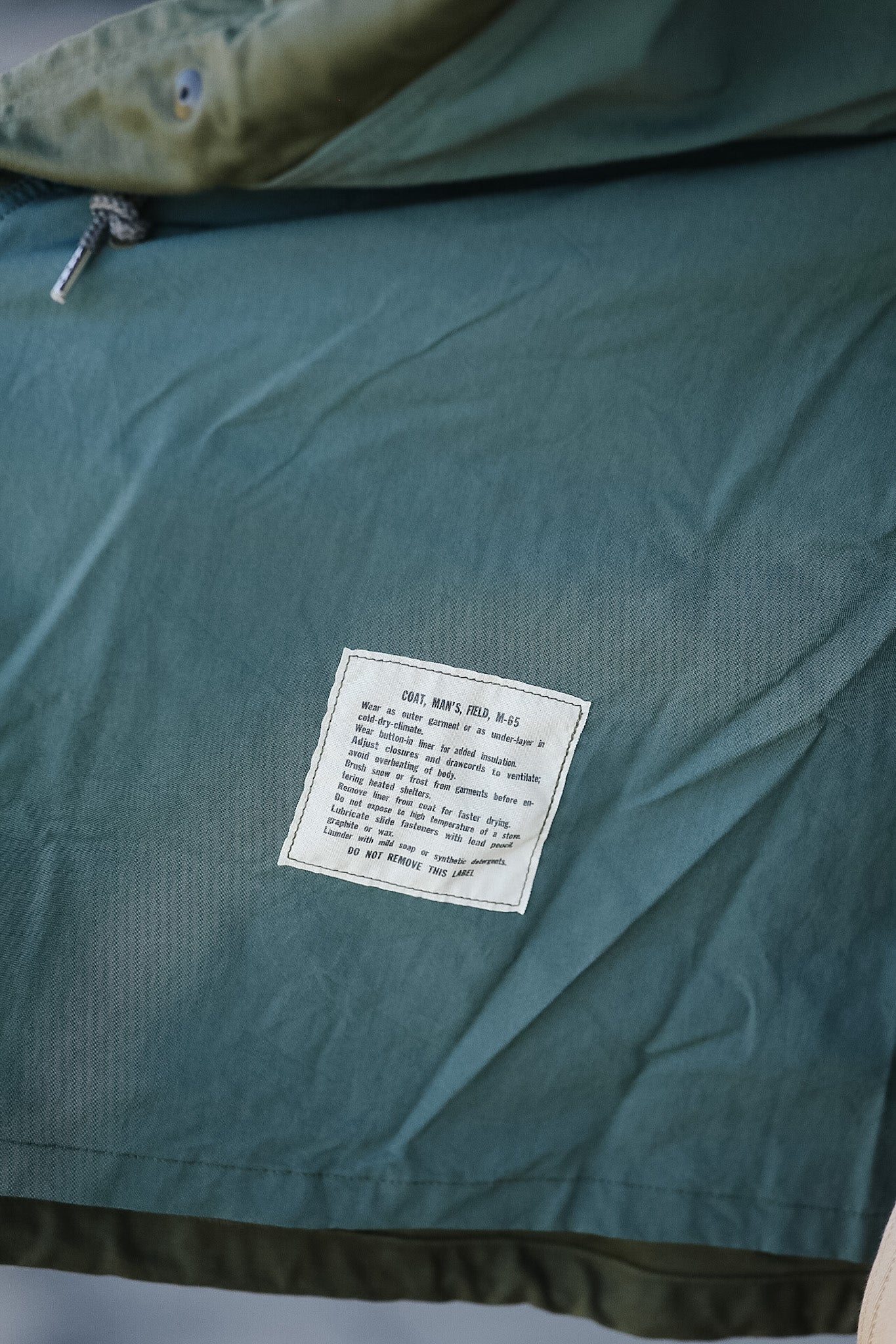 Green jacket with a label on a neutral background