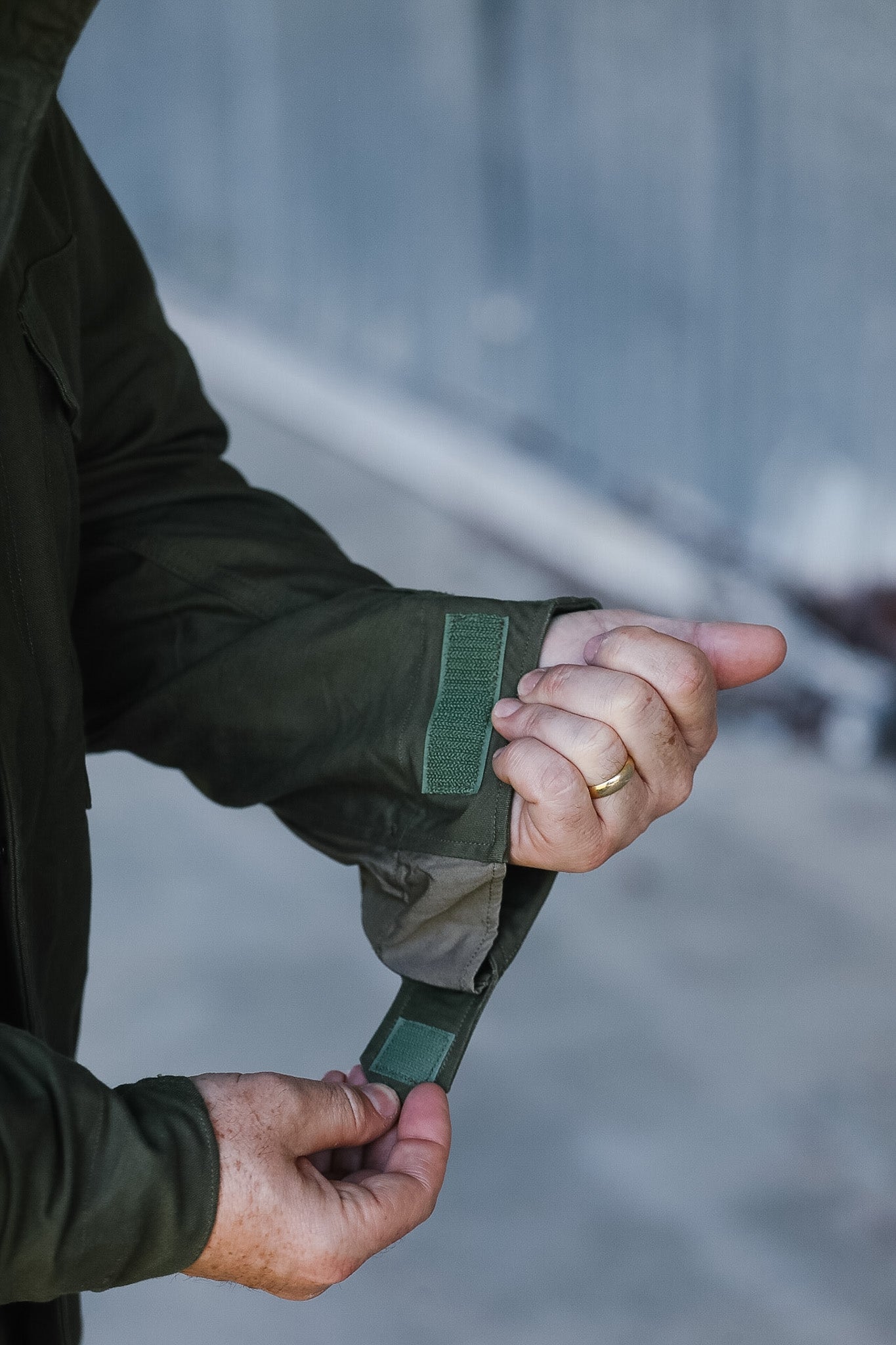 Person adjusting a green strap on a jacket with a blurred background