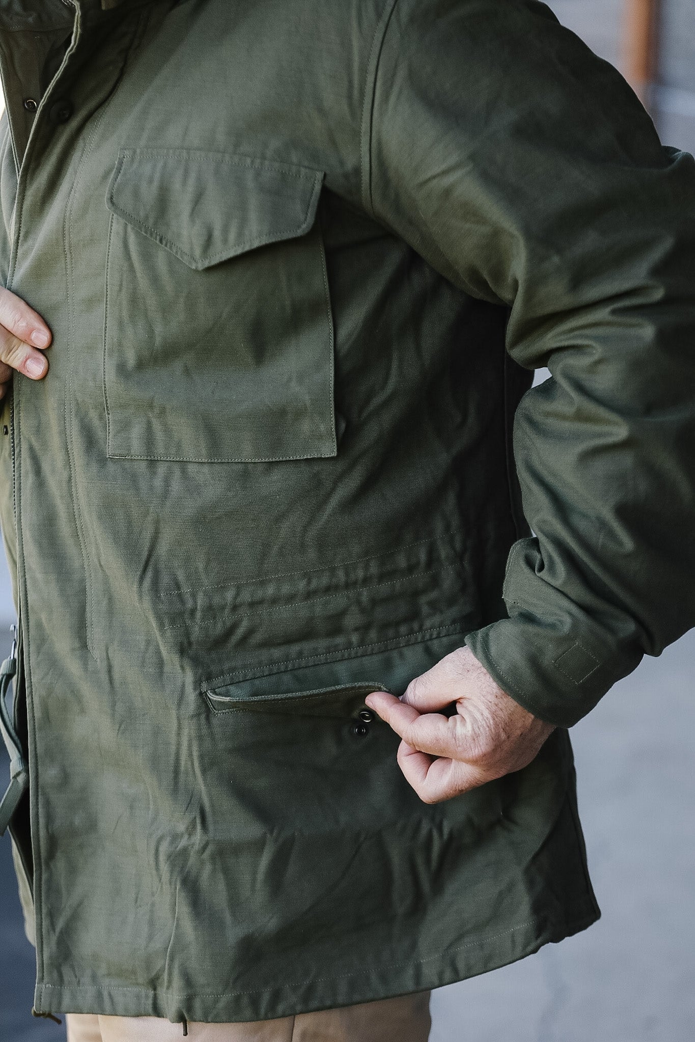 Person wearing a green jacket with a pocket on a neutral background