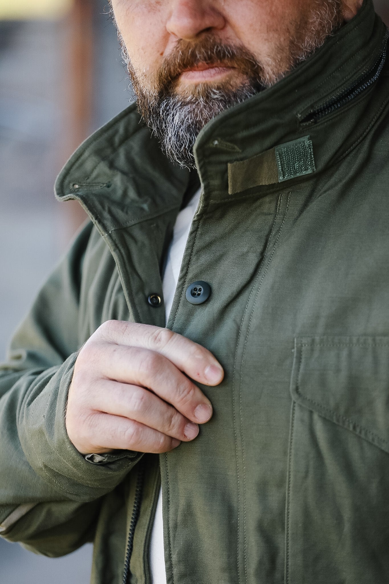 Man wearing a green jacket with a blurred background