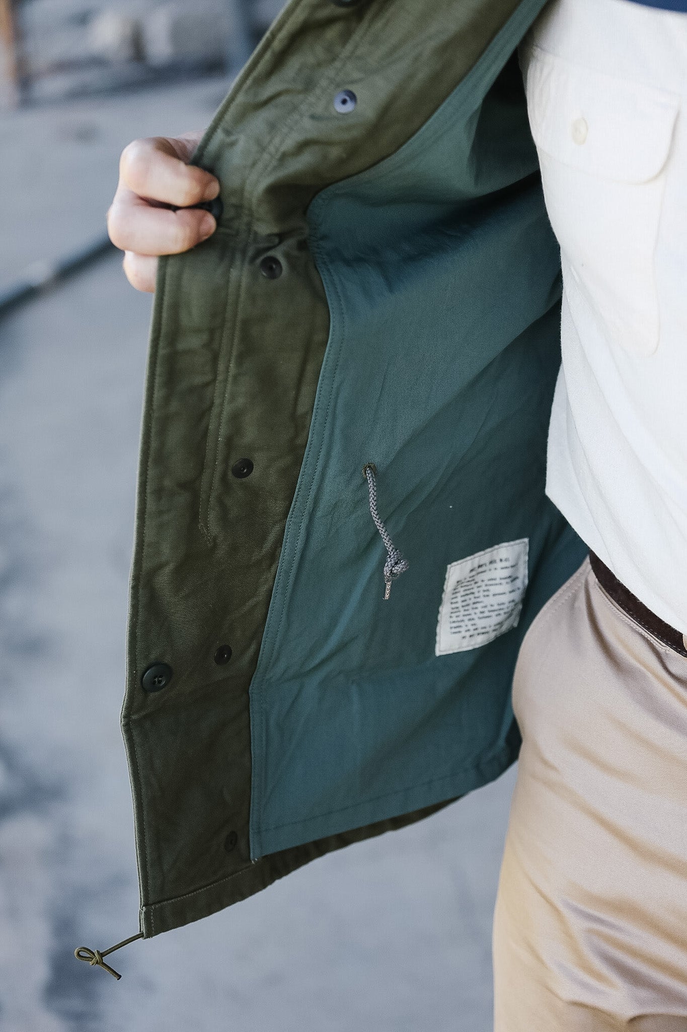 Close-up of a person wearing a green jacket with a blurred background